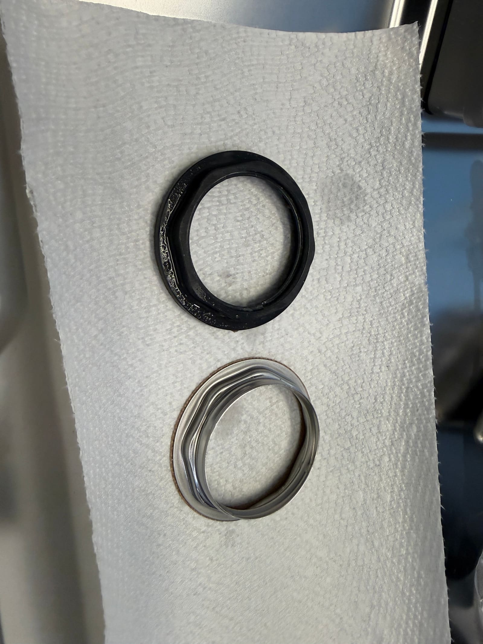 Old plastic zeolite container nut next to the new metal replacement nut