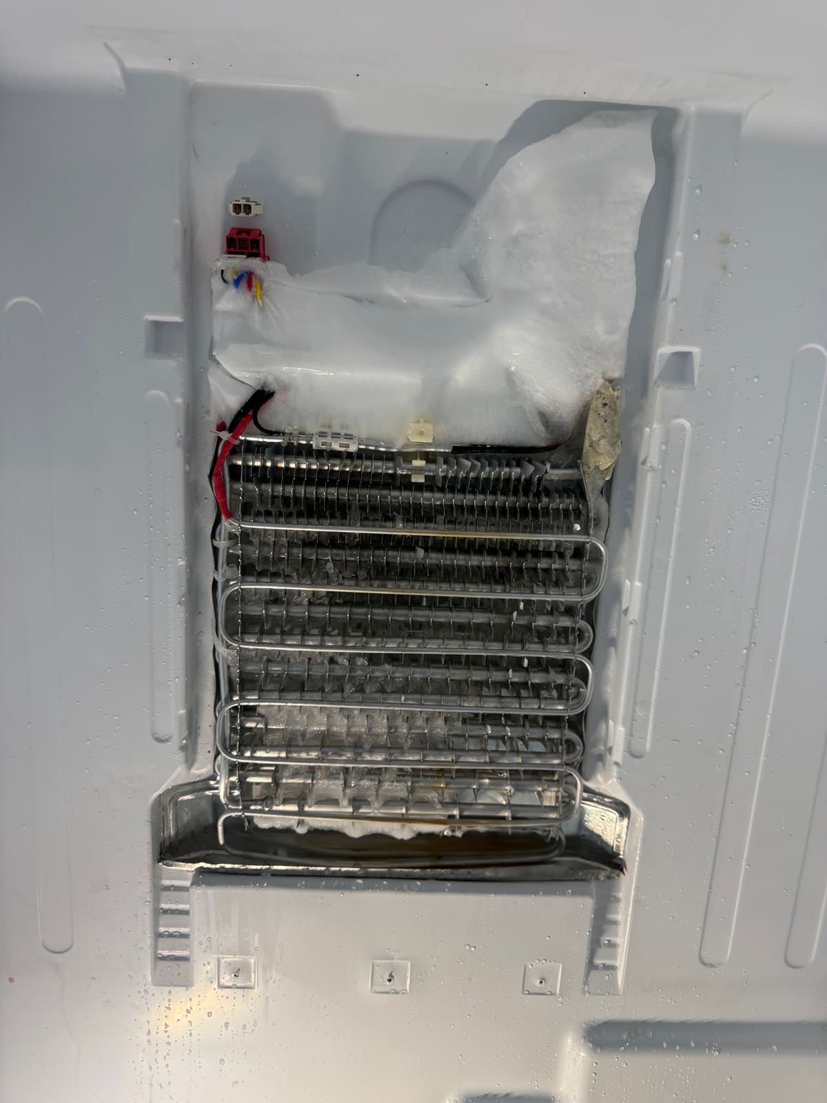 Bosch evaporator coil with the panel off, with a thick block of ice over the top of the coil