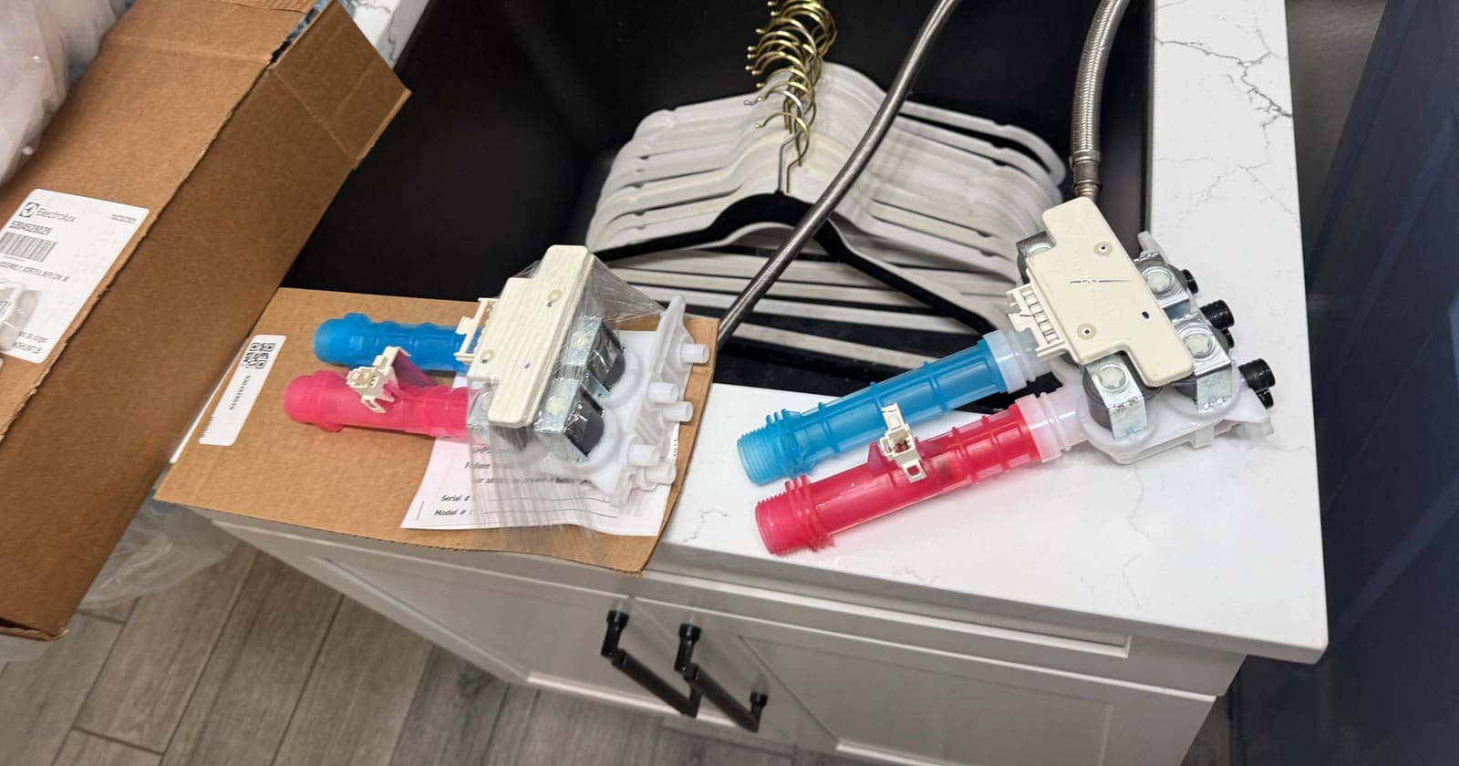 New Electrolux water inlet valve in its packaging on the left and the old valve with its hot and cold inlets on the right