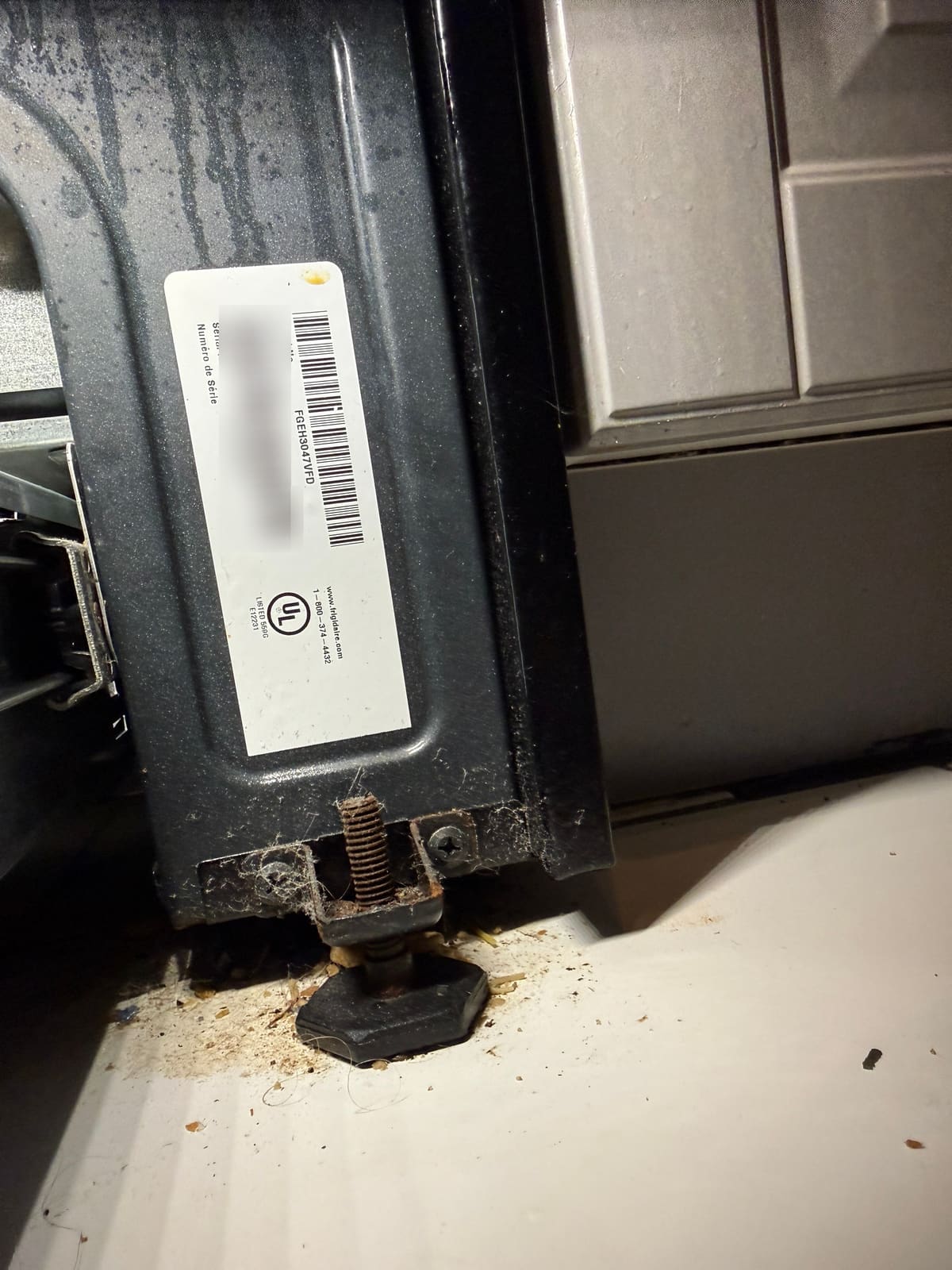 Frigidaire range label behind the storage drawer showing model FGEH3047VFD, with the serial number blurred