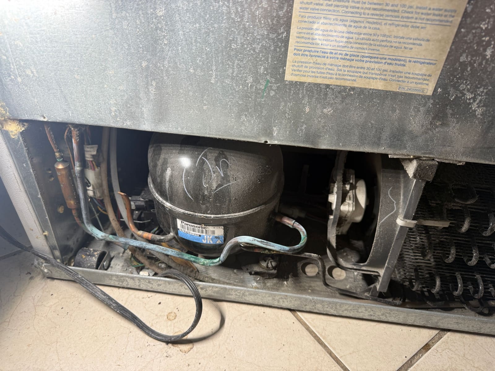 Frigidaire compressor compartment with the rear cover off, showing the Panasonic compressor and the condenser fan