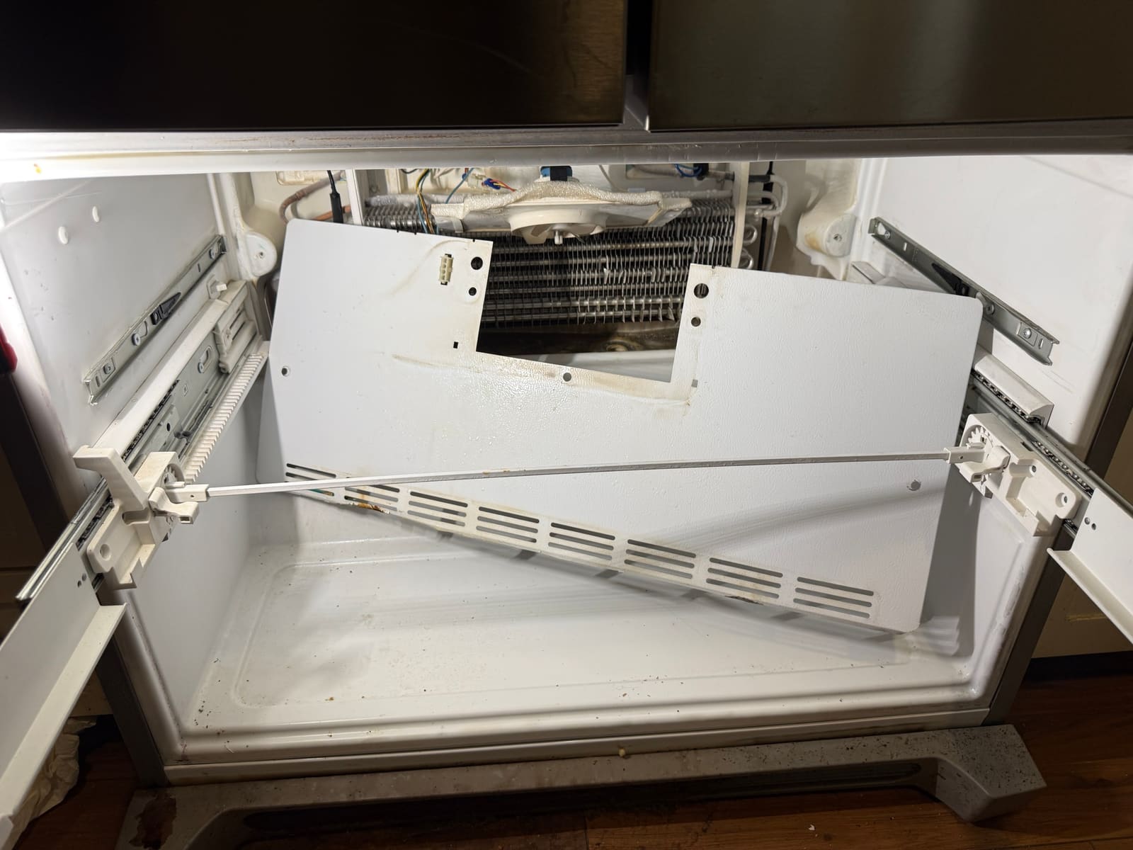 Frigidaire freezer drawer with the rear cover removed, exposing the evaporator coil and the fan housing above it