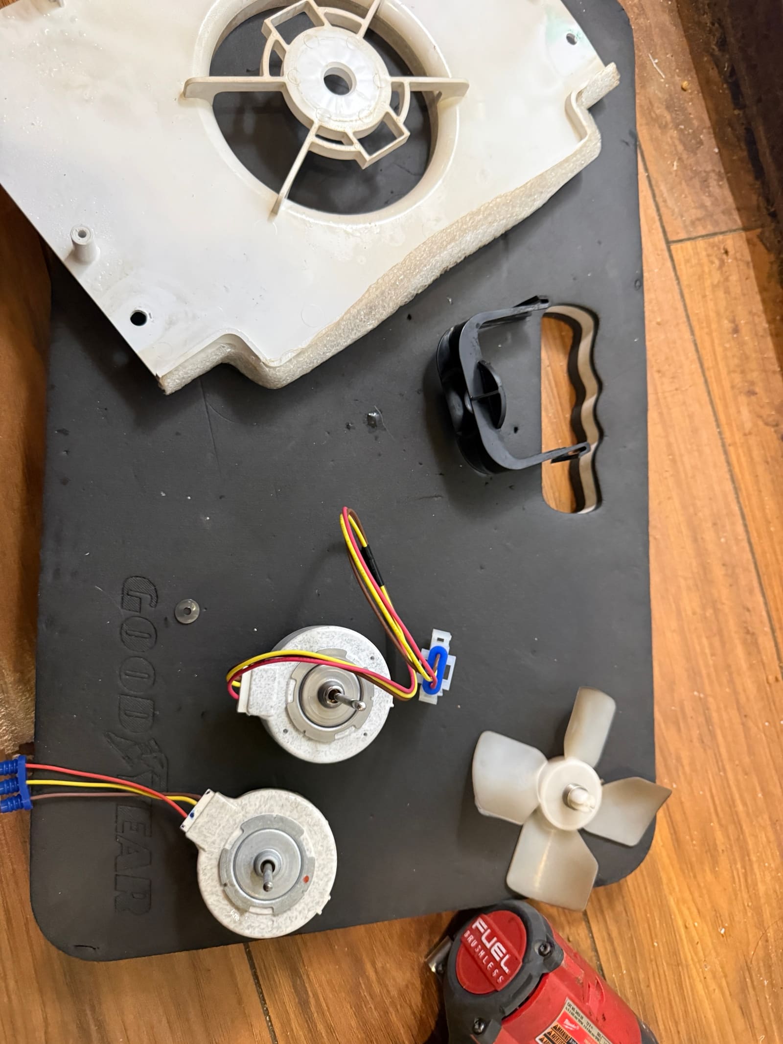 Old and new evaporator fan motors laid out next to the fan blade and the fan housing