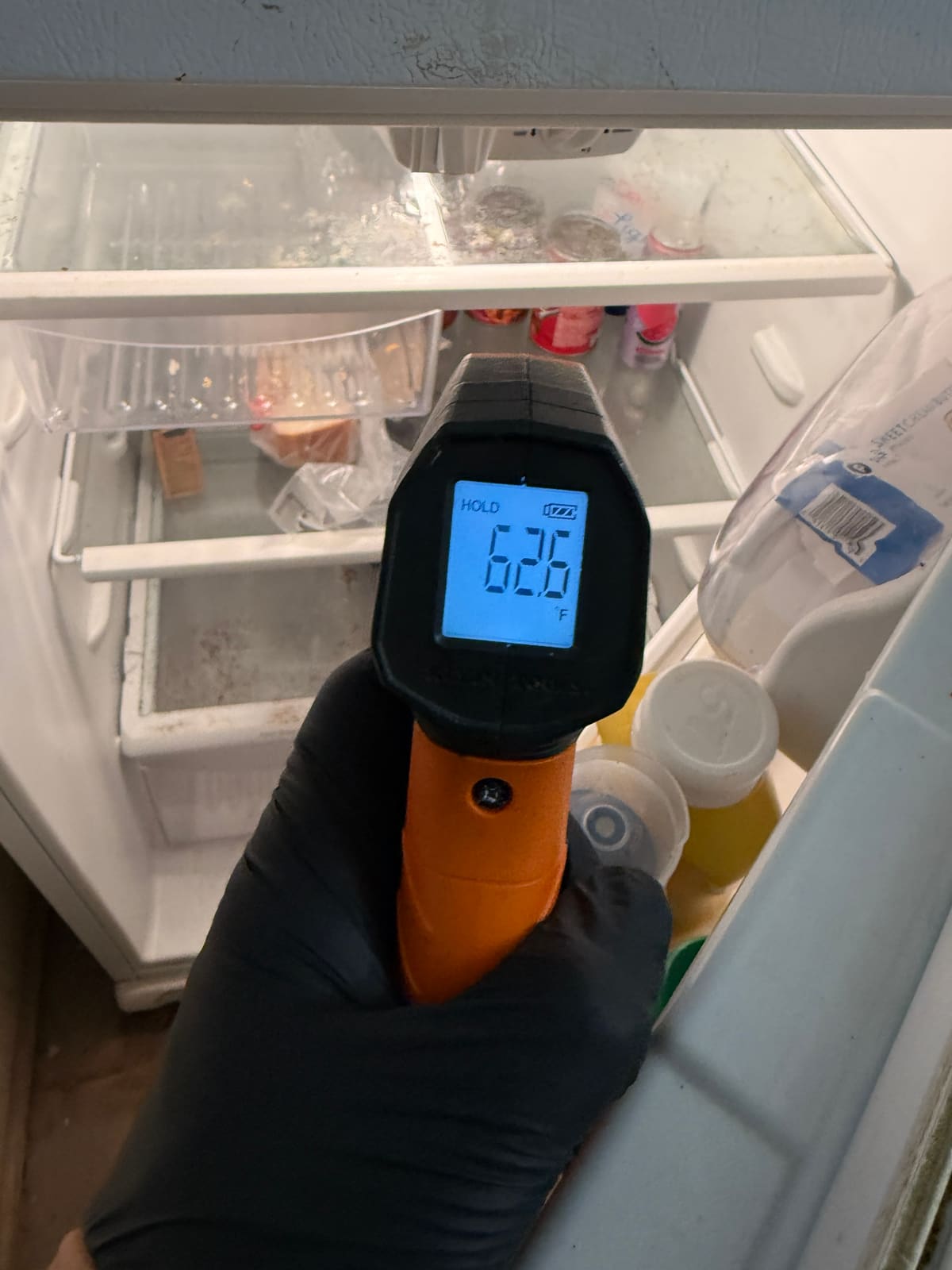 Infrared thermometer reading 62.6°F inside the fresh food section of a Frigidaire refrigerator in Town 'n' Country