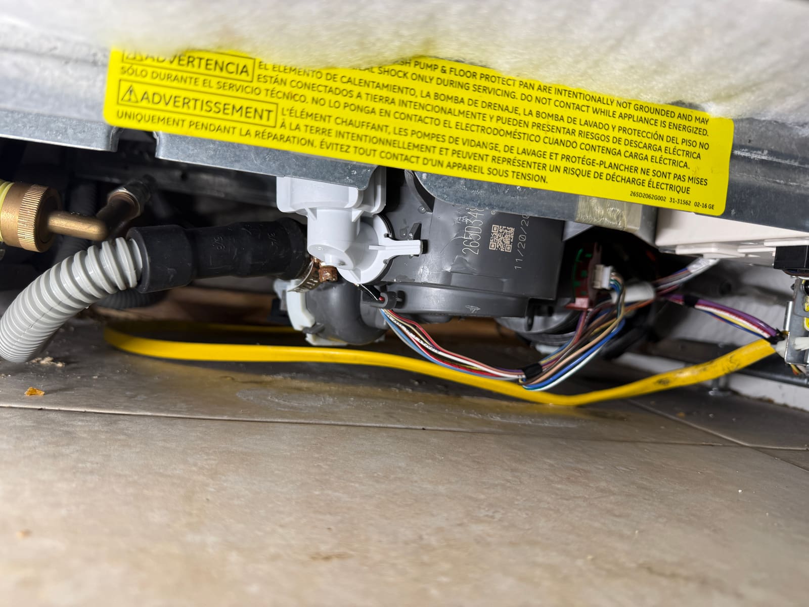 Underside of the GE dishwasher opened up to access the drain pump and sensor