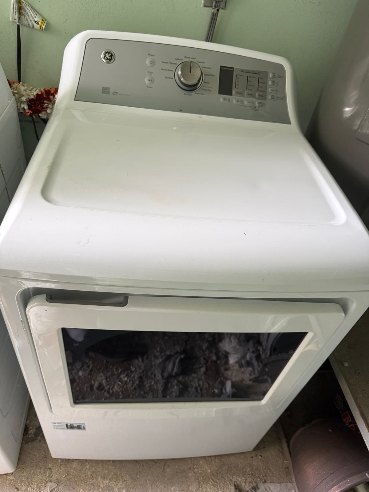 White GE electric dryer with a glass door window in a laundry room in the Woods at Anderson Park neighborhood of Tarpon Springs