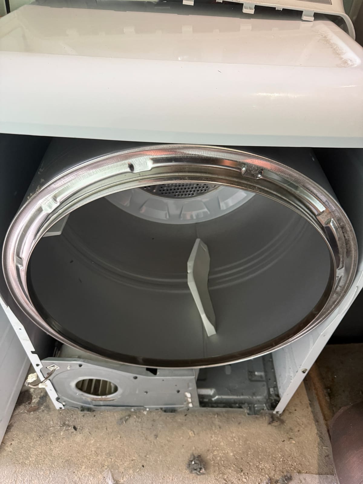 GE dryer with the front panel removed, showing the drum and the blower housing below it