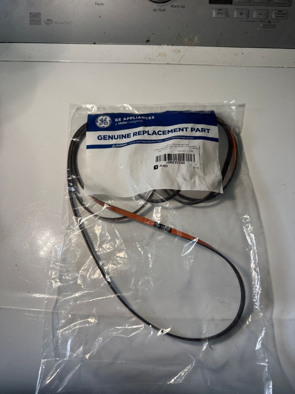 New genuine GE Appliances dryer drive belt, part WE03X29897, in its bag on top of the dryer