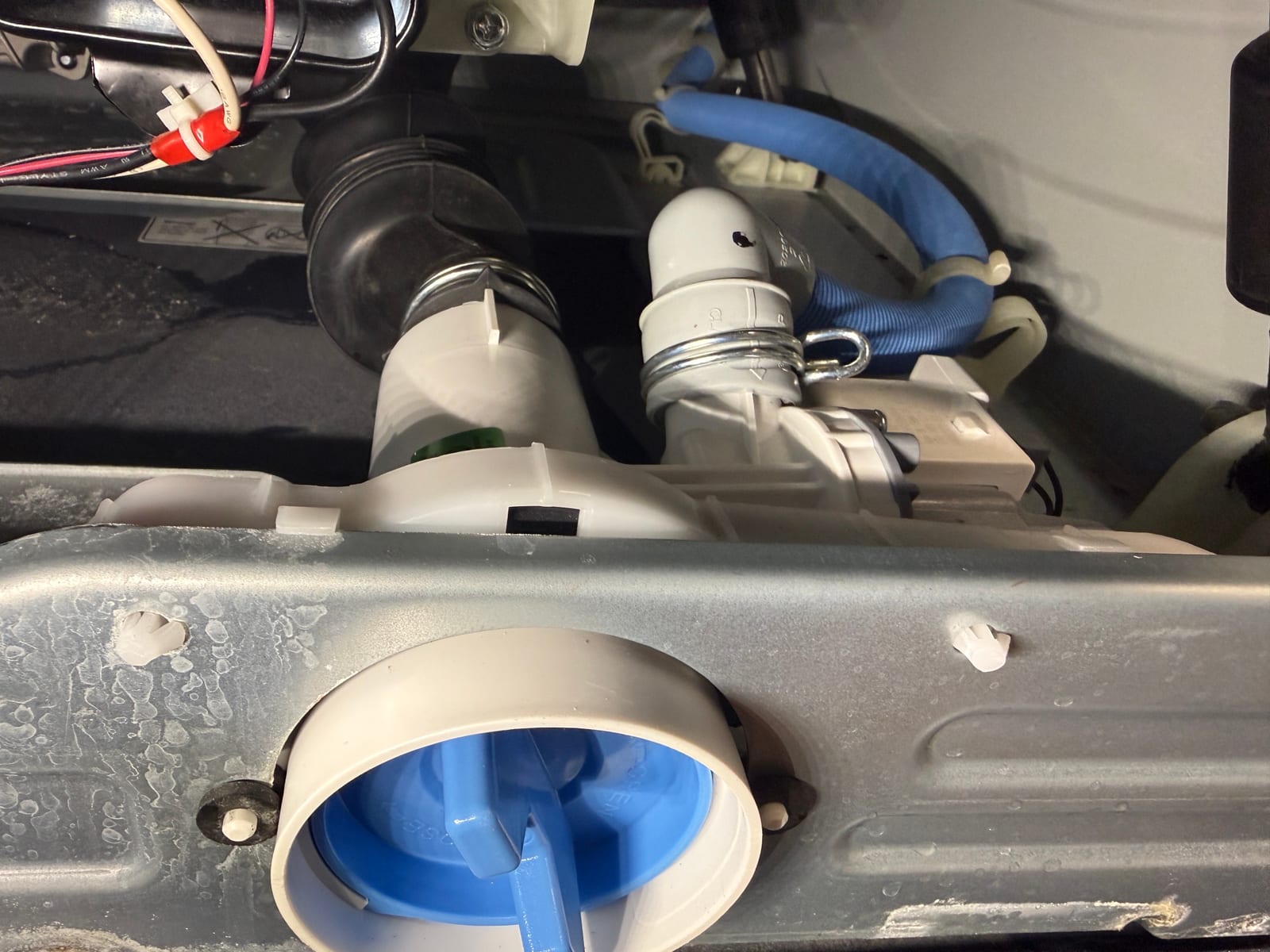 New drain pump installed in the GE washer, with the blue filter cap visible