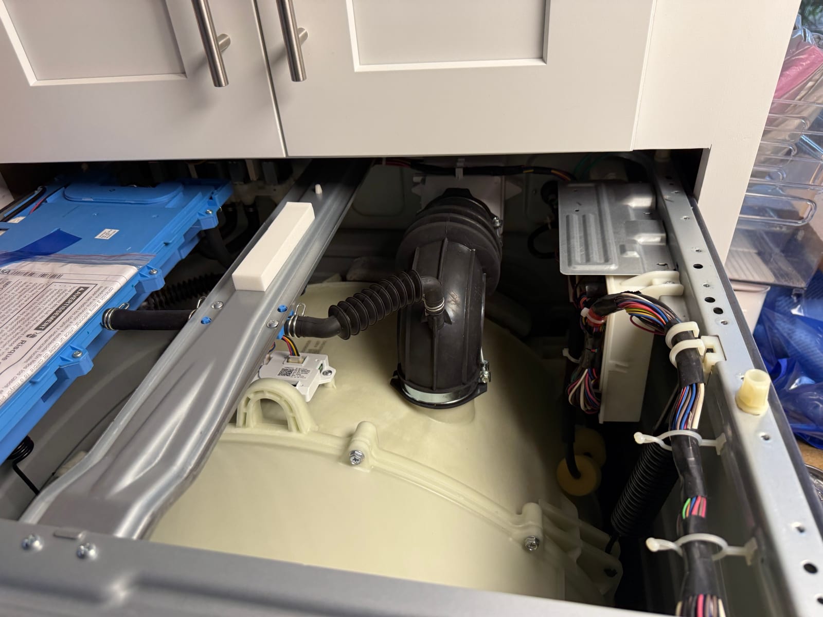 GE washer with the top removed, showing the blue dispenser assembly, drain hose and wiring above the tub