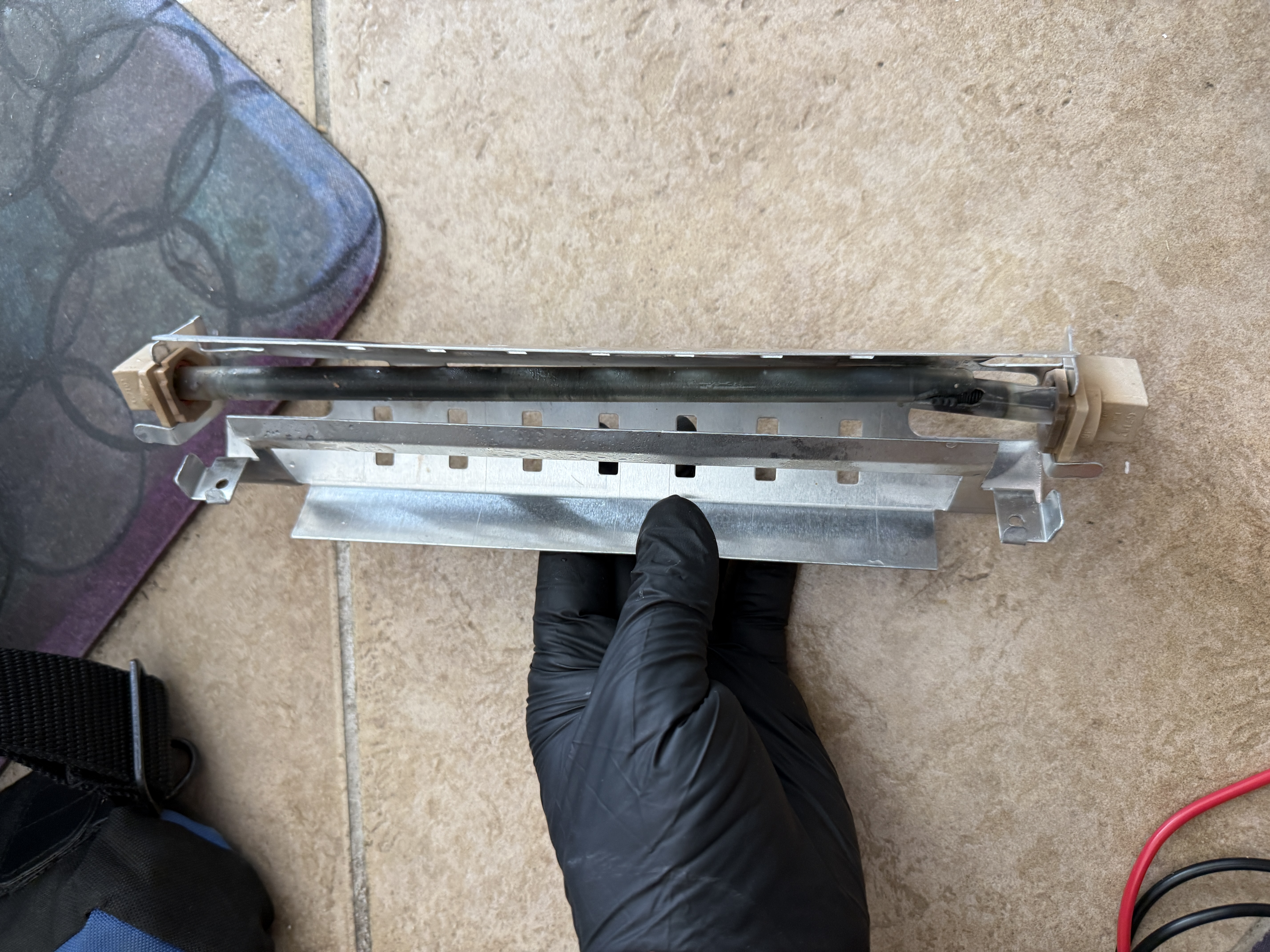 Failed defrost heater removed from the GE refrigerator, with a cracked glass tube