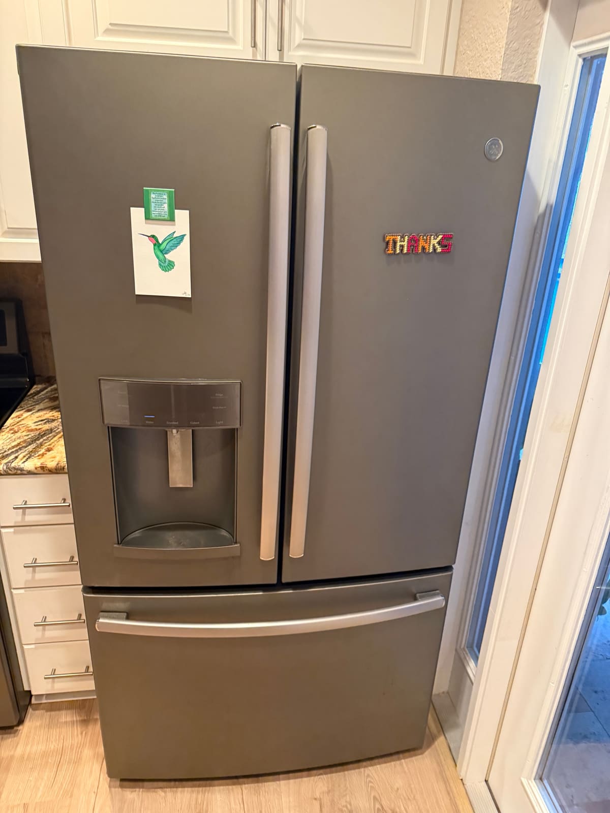 Slate GE French door refrigerator with a door ice and water dispenser and a bottom freezer drawer