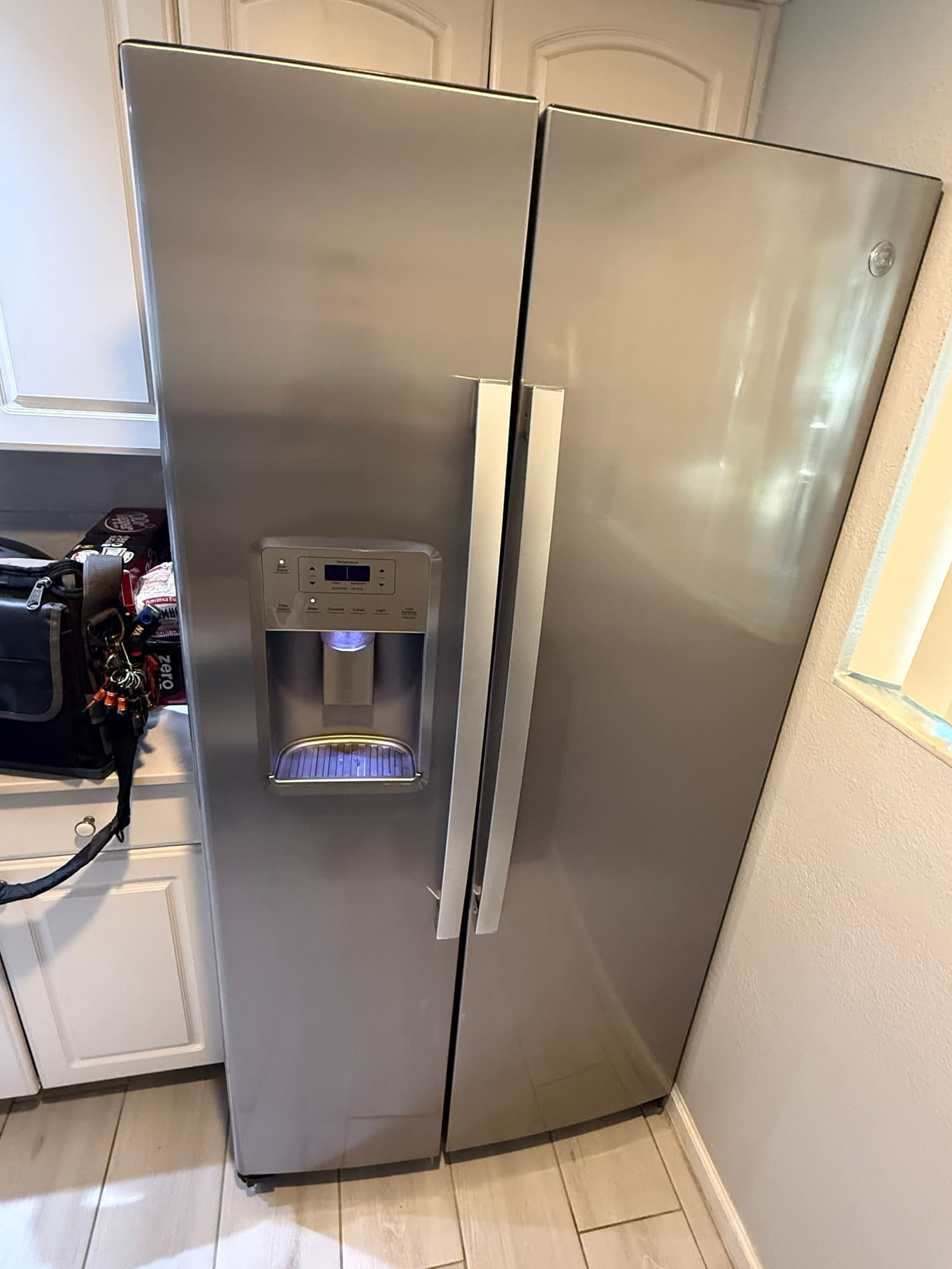 Stainless steel GE side-by-side refrigerator with a door ice and water dispenser in a kitchen in Westchase