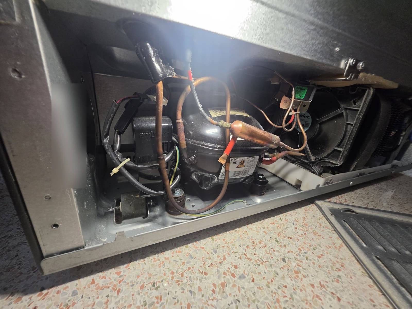 Compressor compartment at the bottom back of the GE Profile refrigerator, showing the Embraco compressor, inverter and condenser fan
