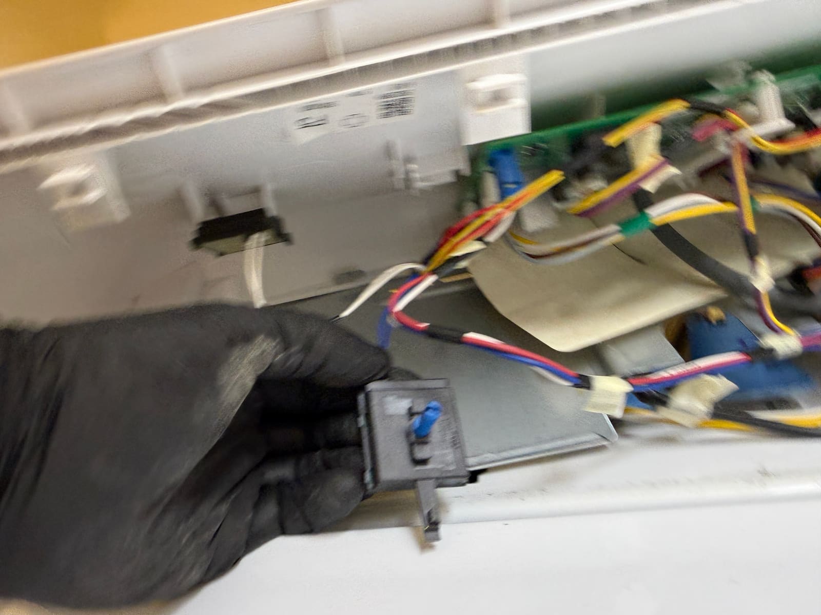 Switch pushed back into the control panel wiring behind the GE washer's dashboard