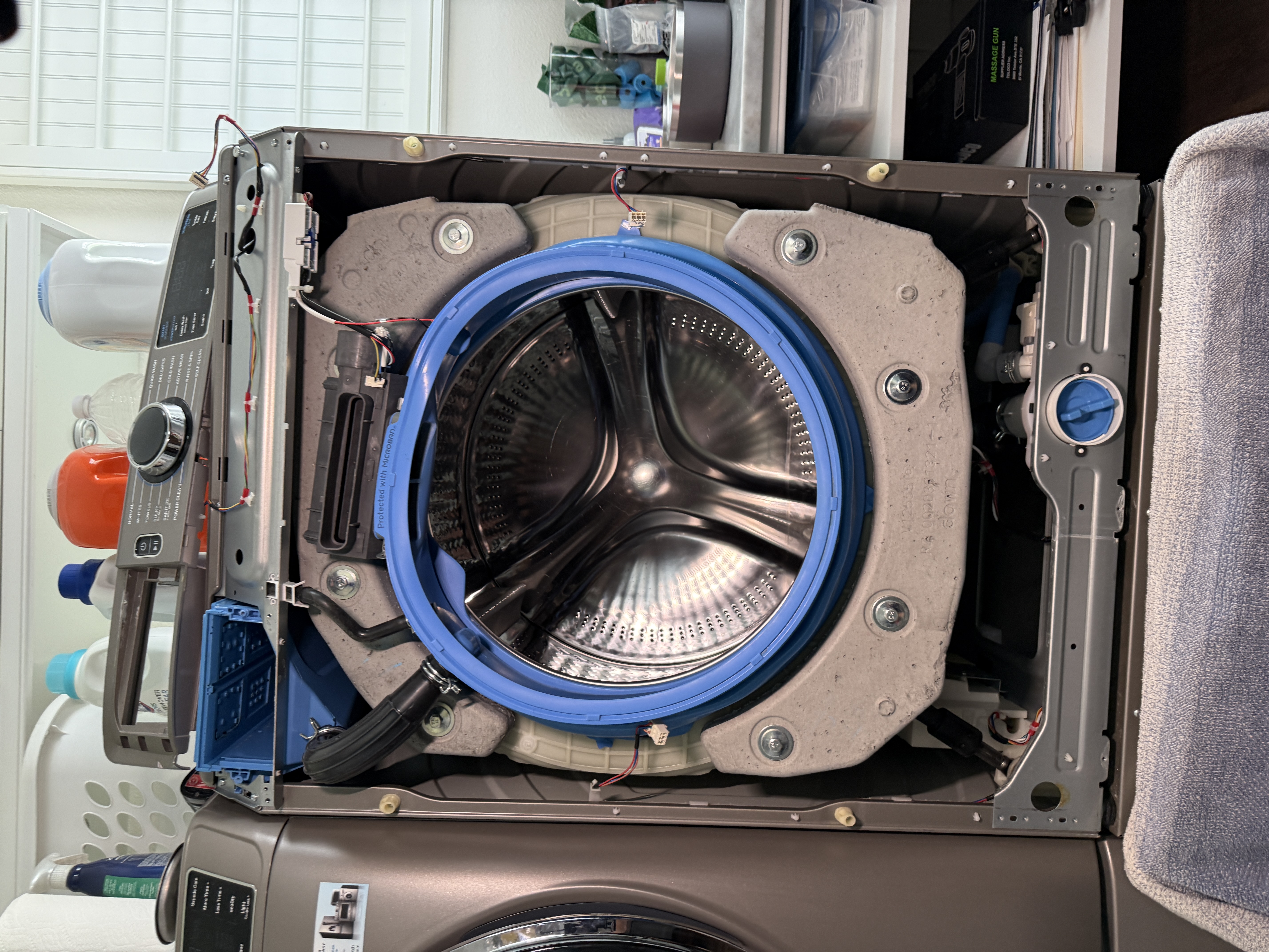 Front panel removed from the GE washer, exposing the tub and drain assembly