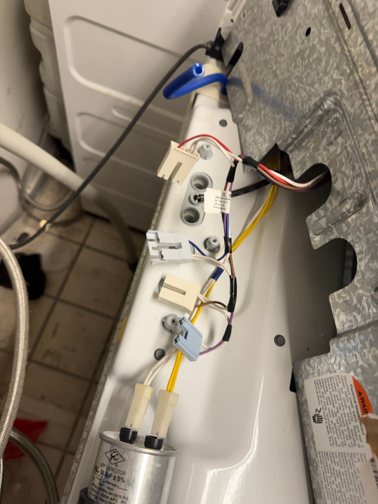 Rear panel of the GE washer open, showing the water valve wiring and connections during diagnosis