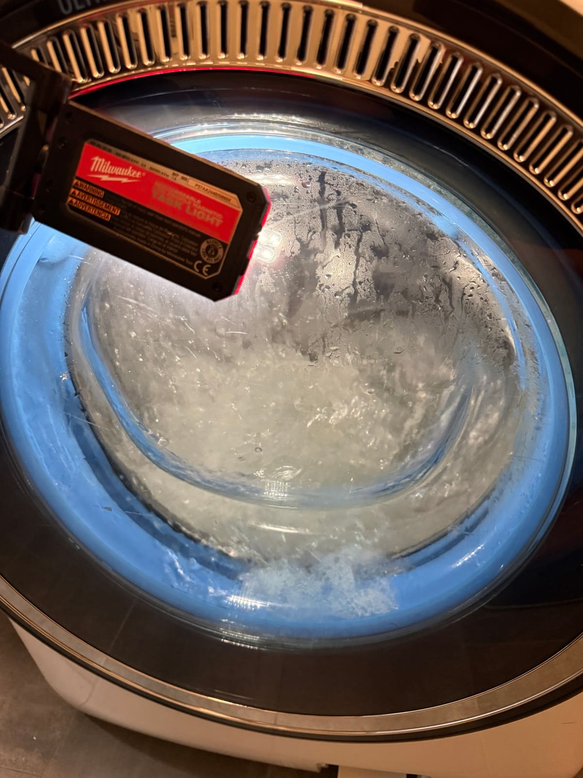 GE front-load washer drum filled with soapy water during a test cycle, shown through the door glass