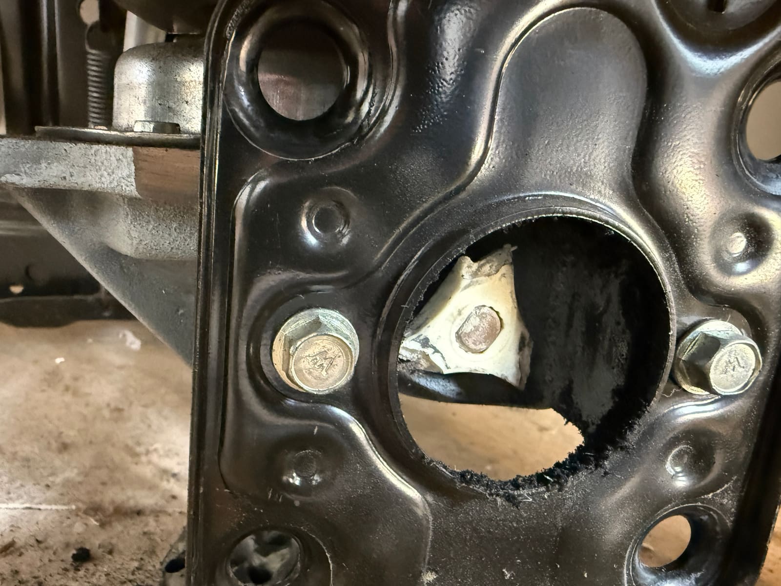 Broken white plastic coupling fork still on the transmission shaft, seen through the Kenmore washer's motor mounting plate