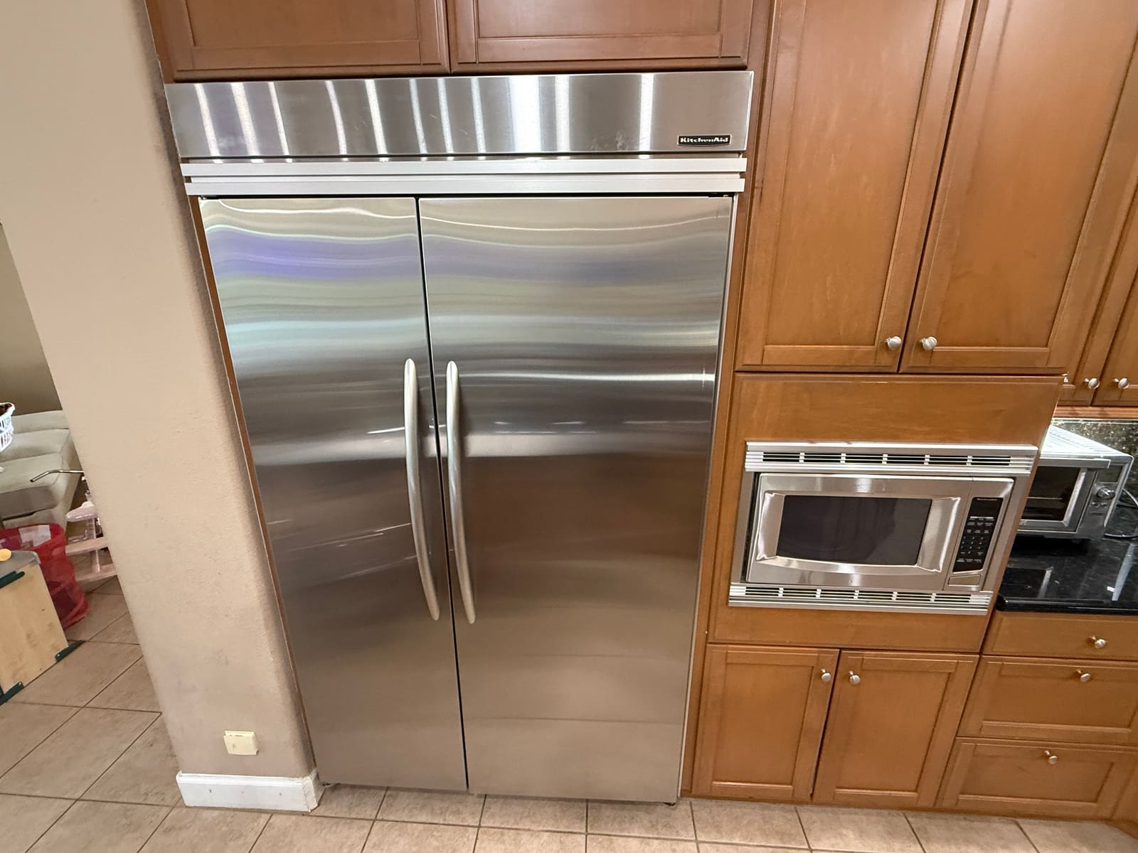 KitchenAid built-in side-by-side refrigerator with stainless doors set into wood cabinetry in a kitchen in Palm Harbor