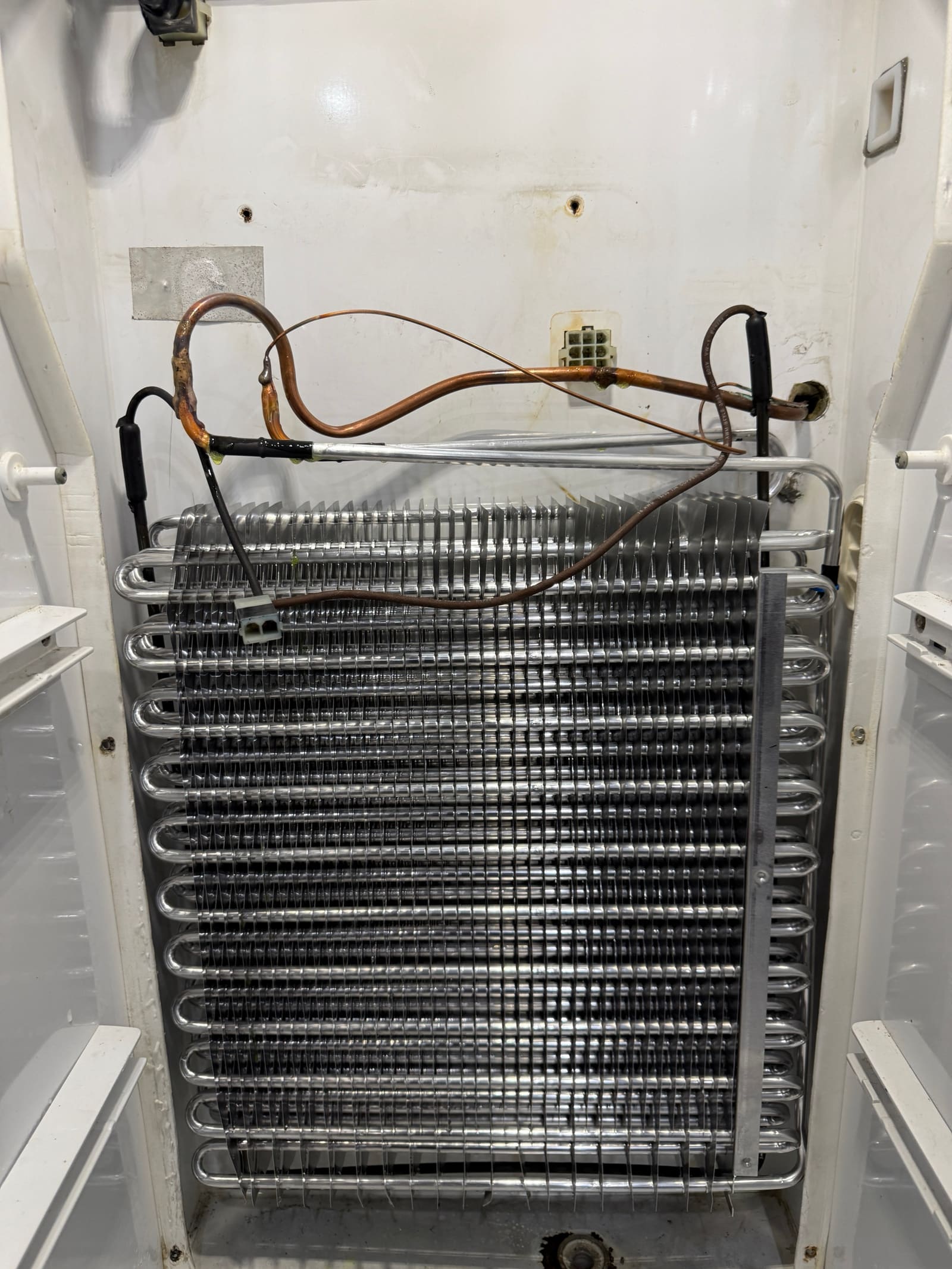 New evaporator coil installed in the KitchenAid freezer with freshly brazed copper connections
