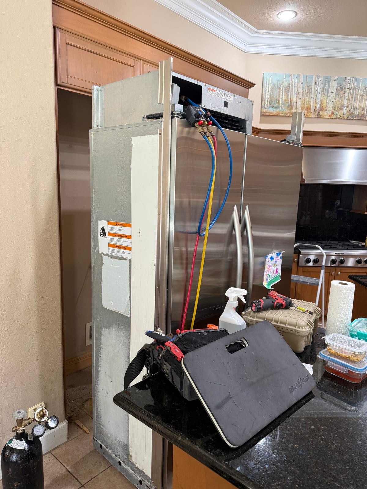 KitchenAid built-in pulled out of its cabinet opening in the kitchen, with a gauge set hooked up on top and tools on the counter