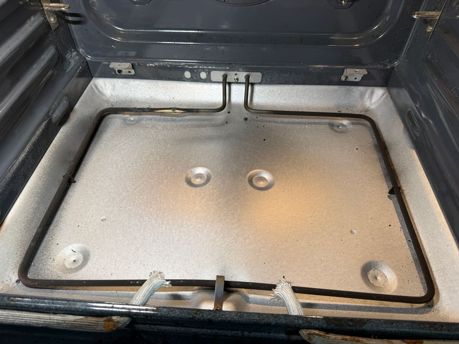 Hidden bake element under the KitchenAid oven floor panel with a burned-through section along the back