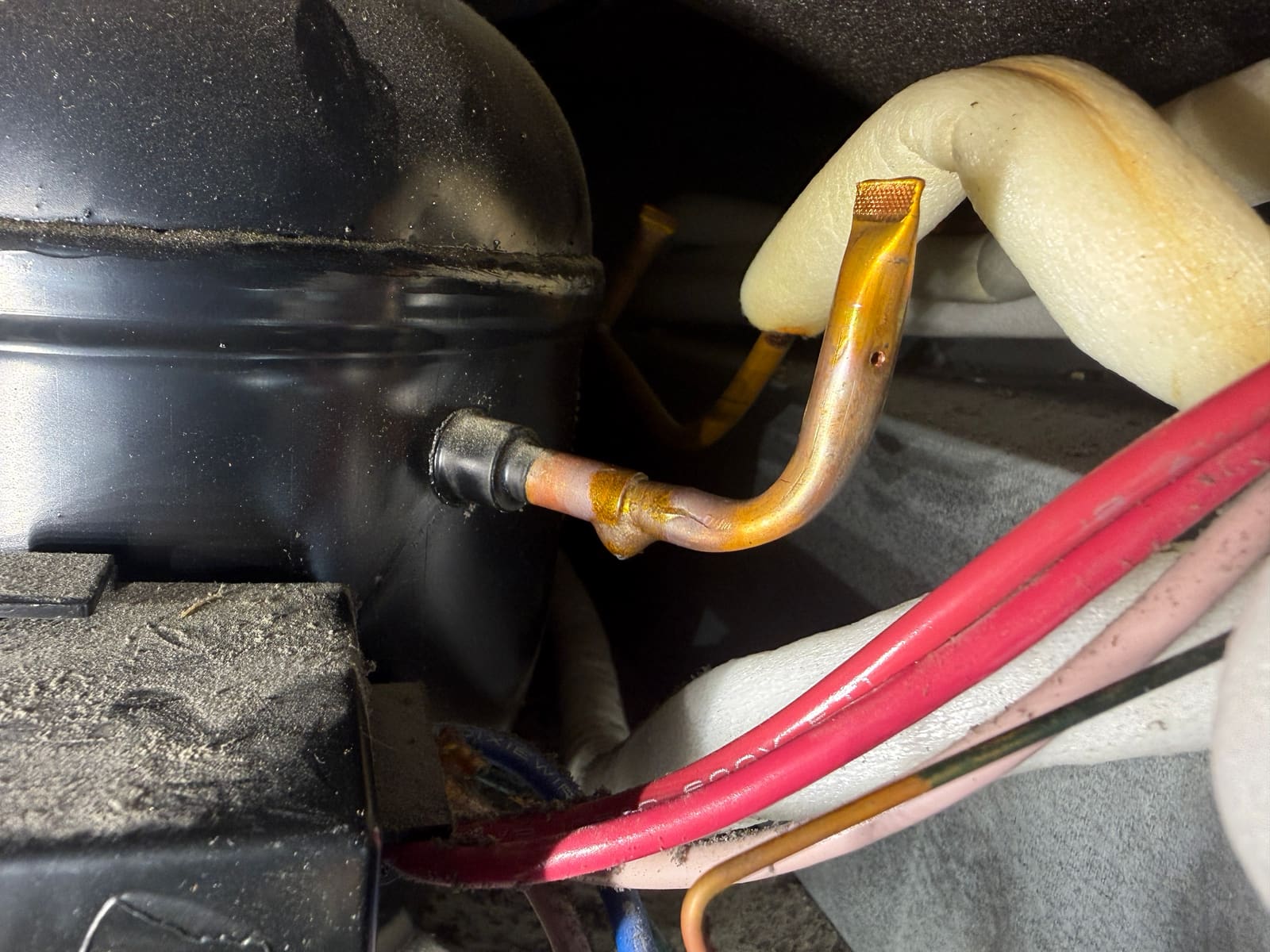 Checking refrigerant line joints near the compressor during leak diagnosis