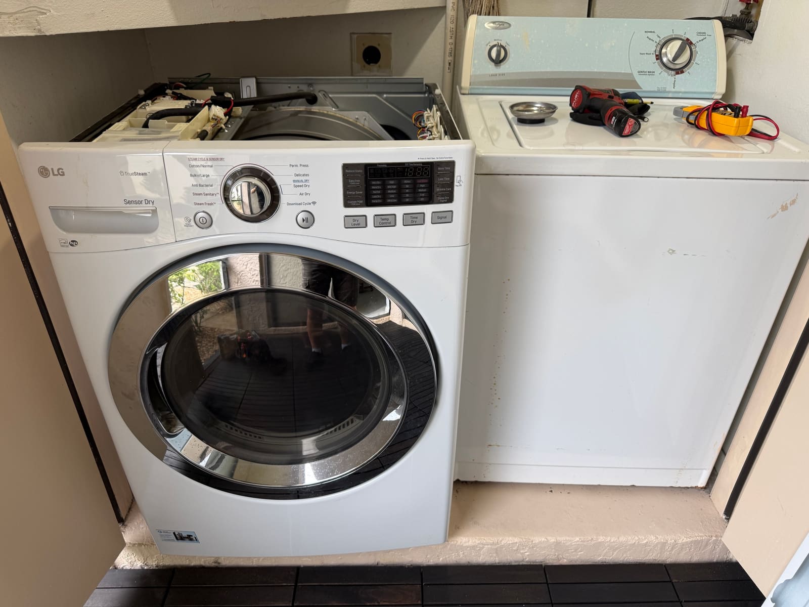 LG front-load electric dryer with the top panel removed, next to a Whirlpool washer, in the Westmonte Estates neighborhood of Palm Harbor