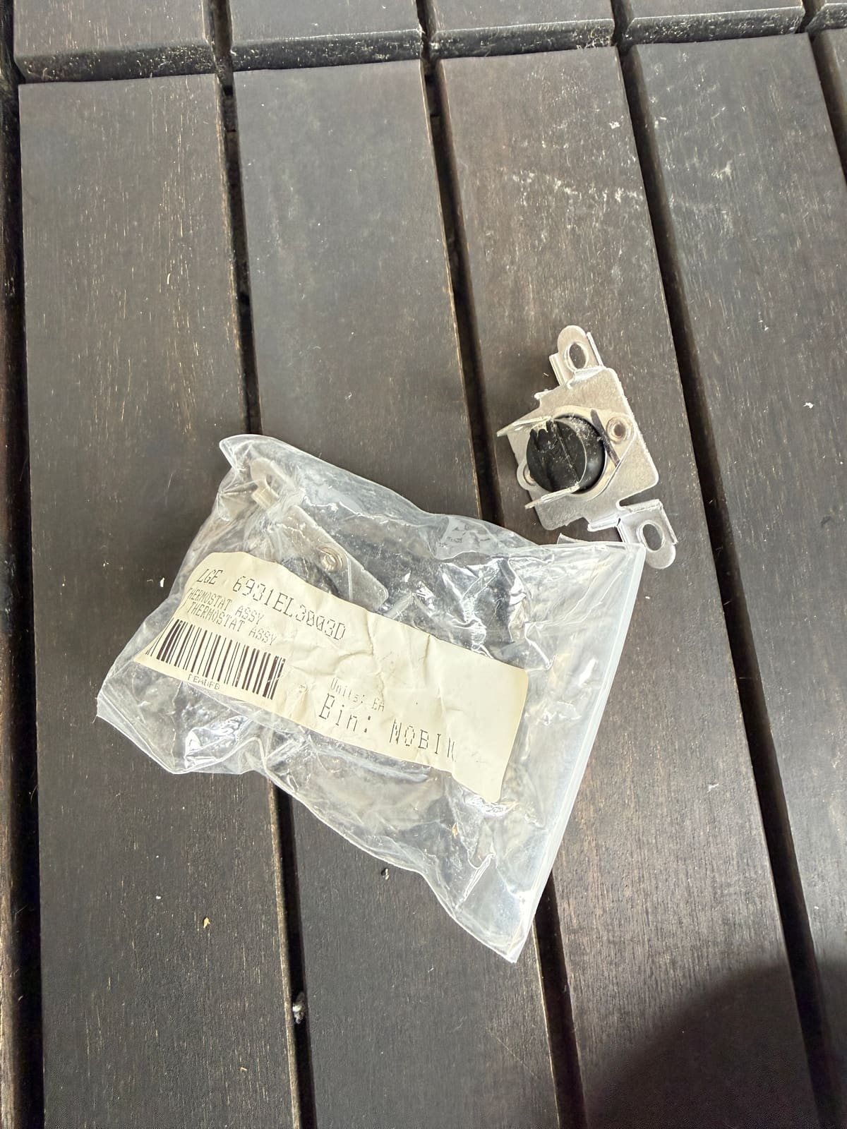 New LG high limit thermostat, part 6931EL3003D, in its bag next to the old thermostat