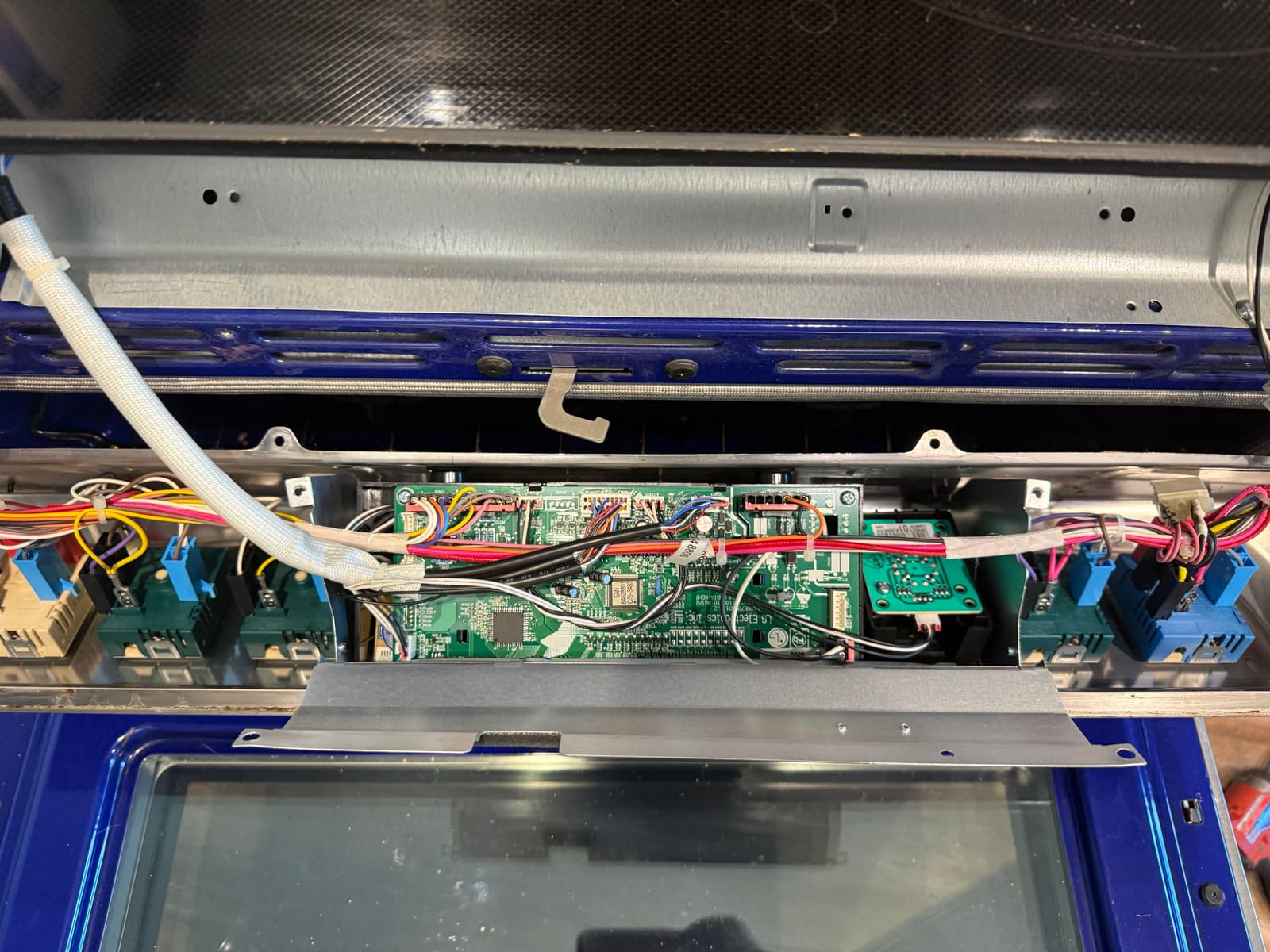LG range control panel opened up, showing the display board, burner switches and wiring