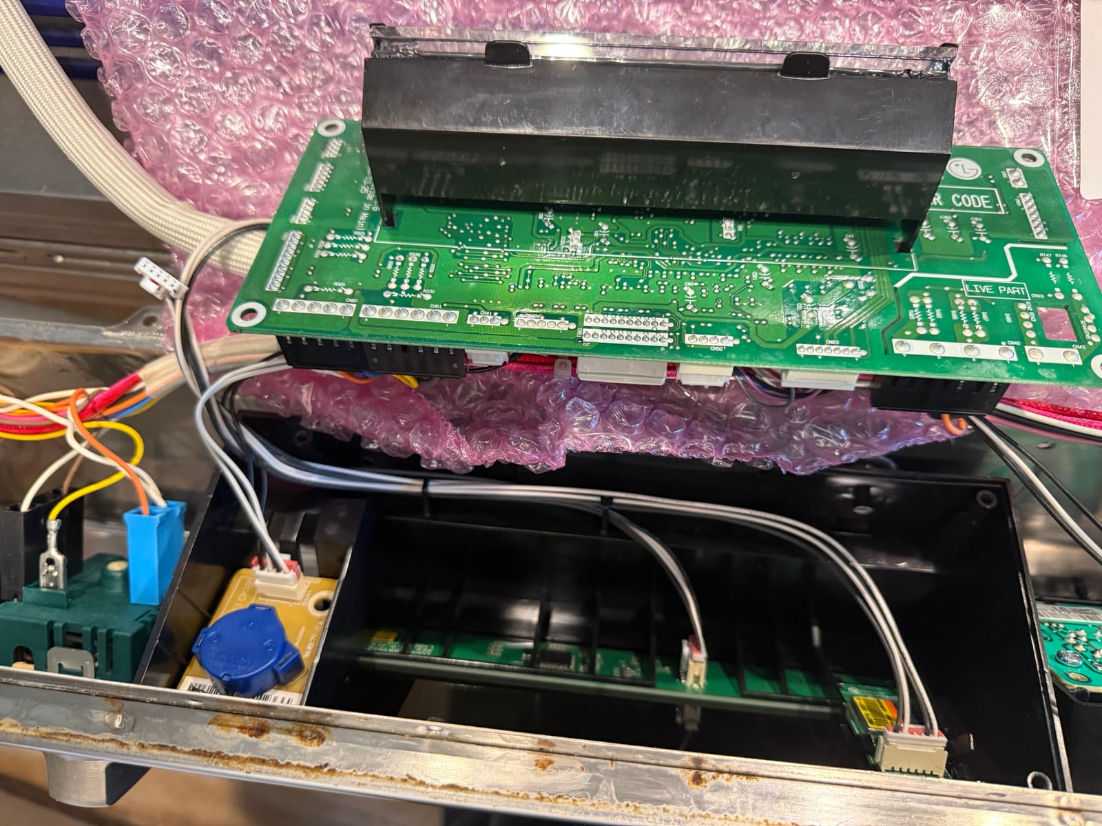 LG display board lifted out of the control housing during the swap, with the wiring still connected
