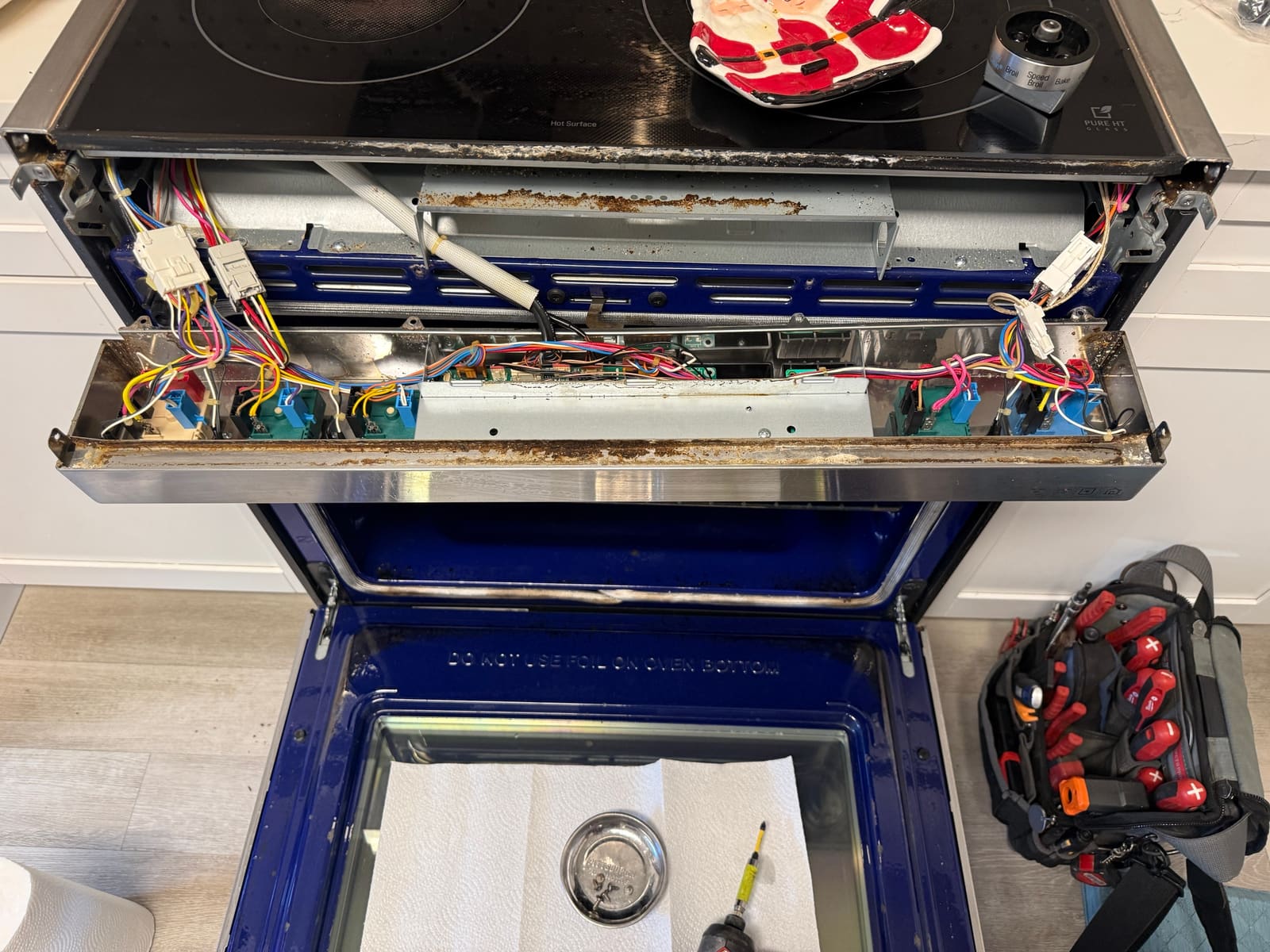 Control panel of an LG electric range opened up, showing the switches and wiring behind the knobs