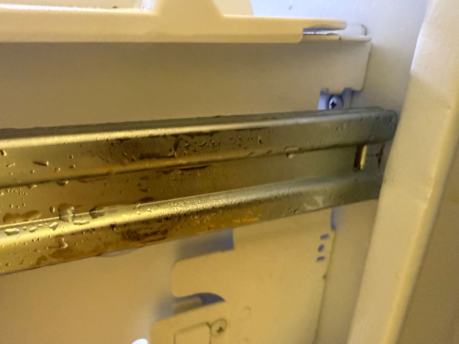 Close-up of an LG freezer drawer slide with water droplets and dirt on the metal