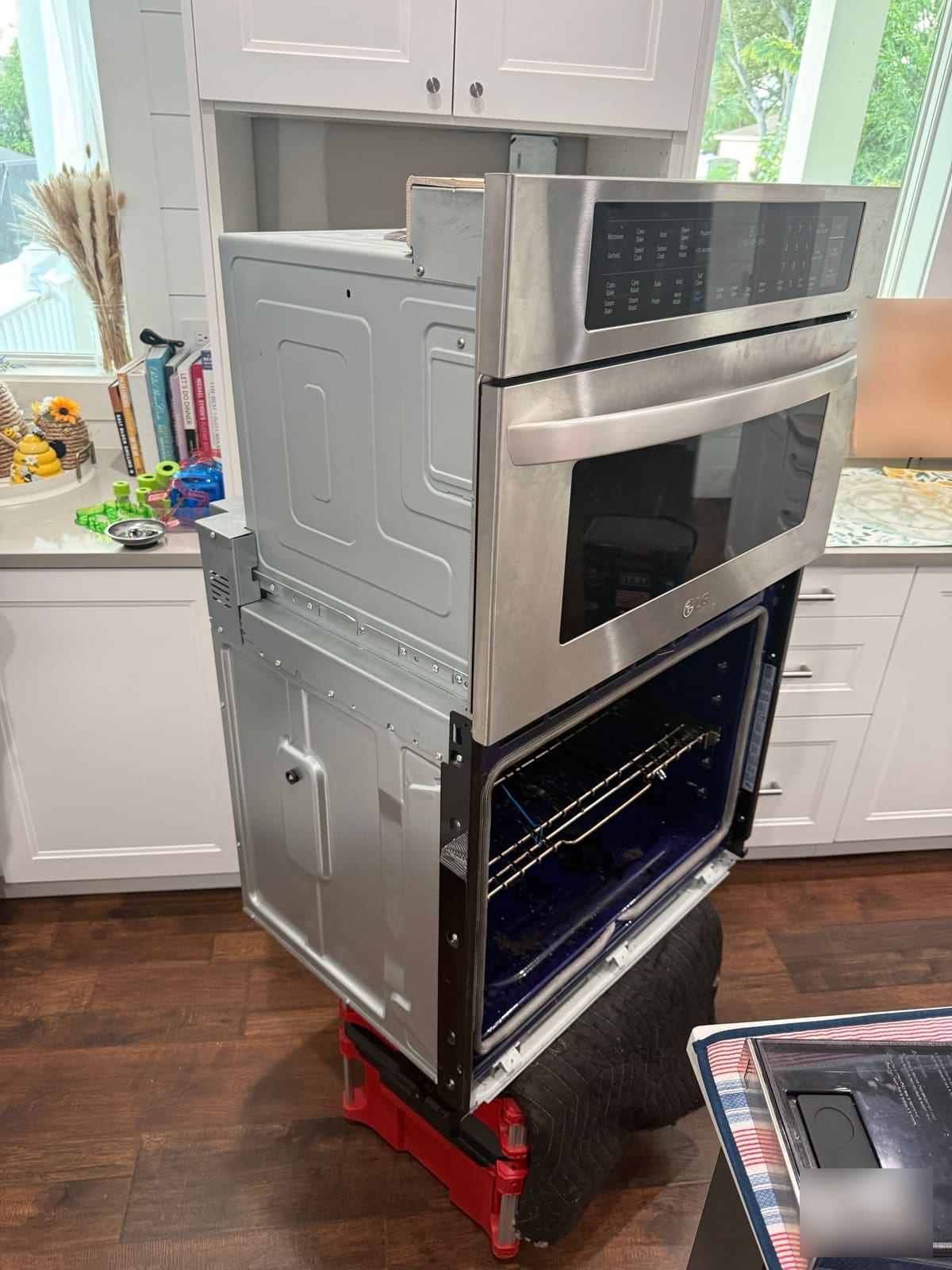 LG microwave and wall oven combo pulled partly out of the cabinet and set on a stand for repair