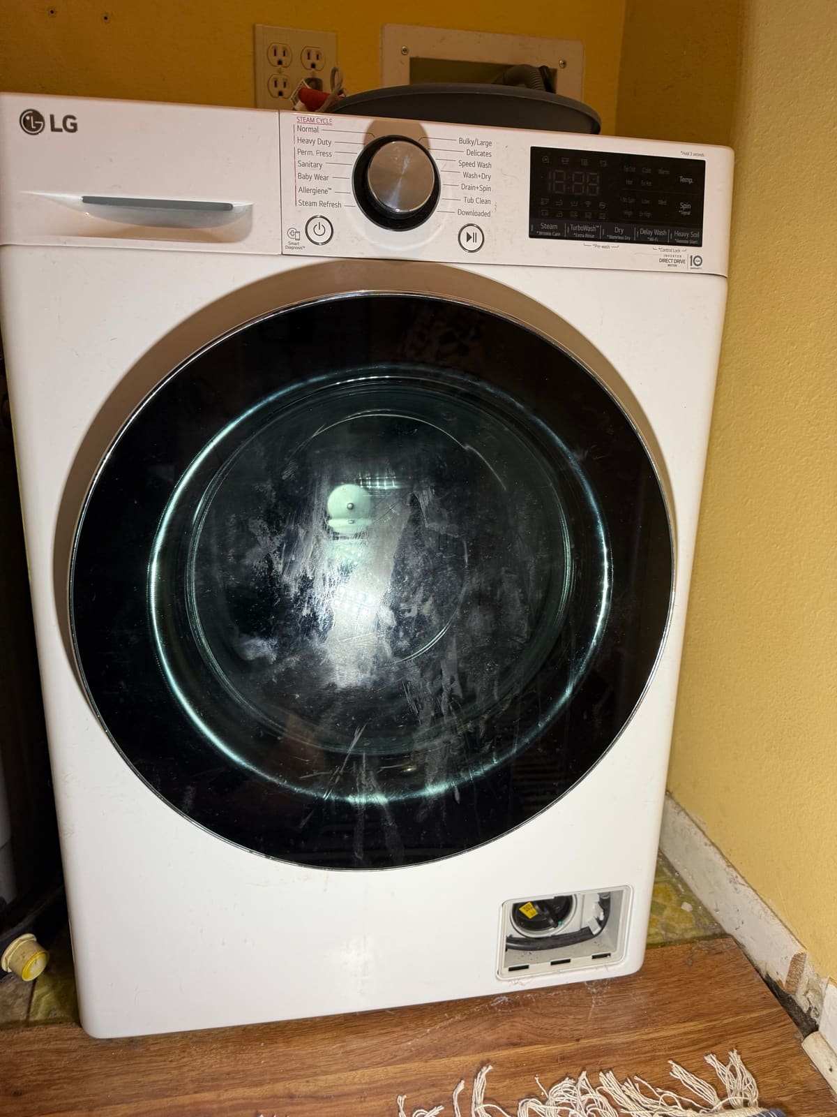 LG all-in-one washer-dryer combo with the drain filter access door open, in a laundry corner in the Countryside Mall area of Clearwater