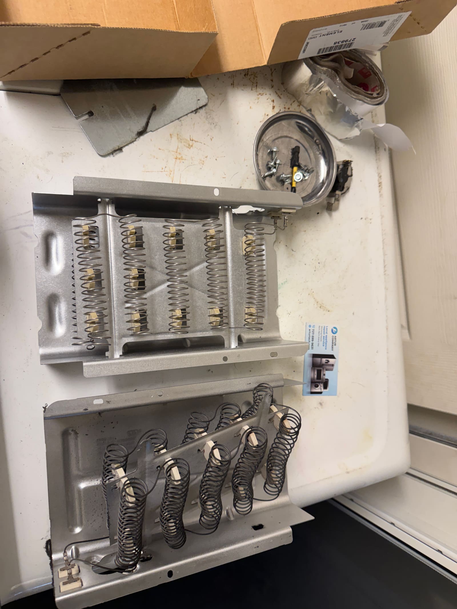 Old and new Maytag dryer heating element assemblies side by side on a workbench