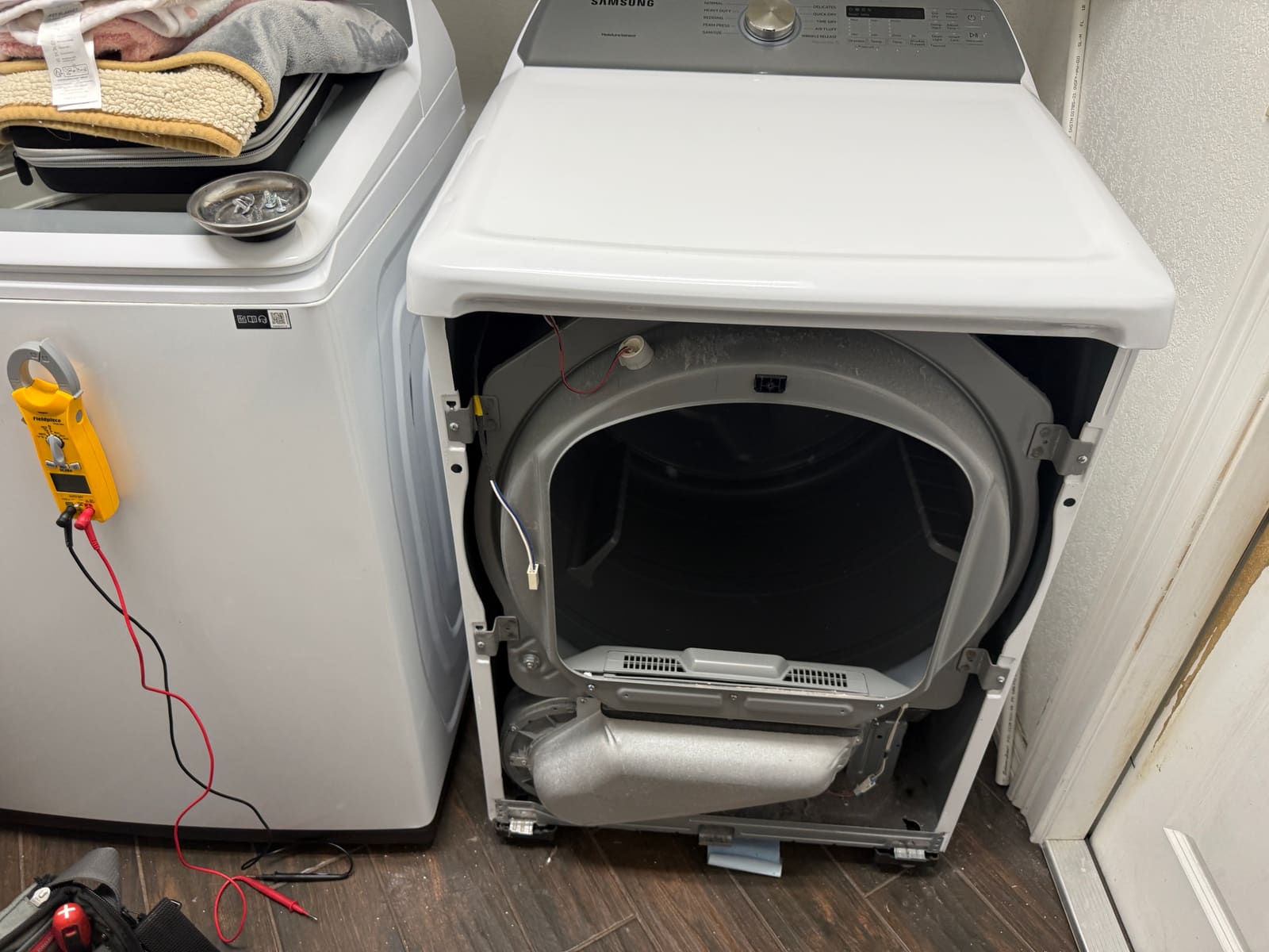 Samsung dryer with the front panel removed, exposing the drum and the bottom of the cabinet