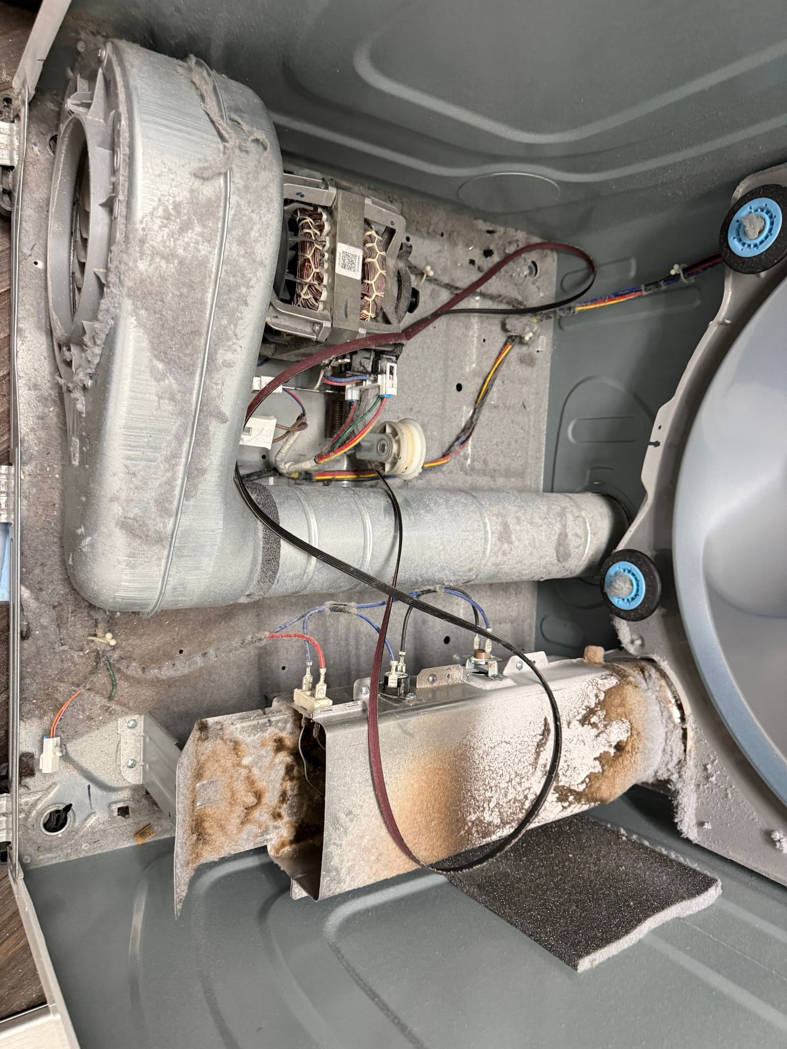 Inside the Samsung dryer cabinet with the drum removed, showing the heater can, blower housing, motor, and built-up lint