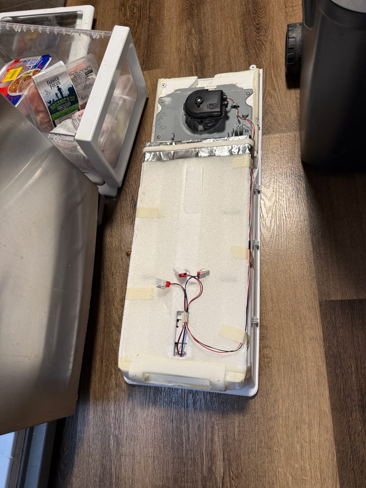 Freezer evaporator fan and housing sitting on the floor, removed from the rear panel of the Samsung