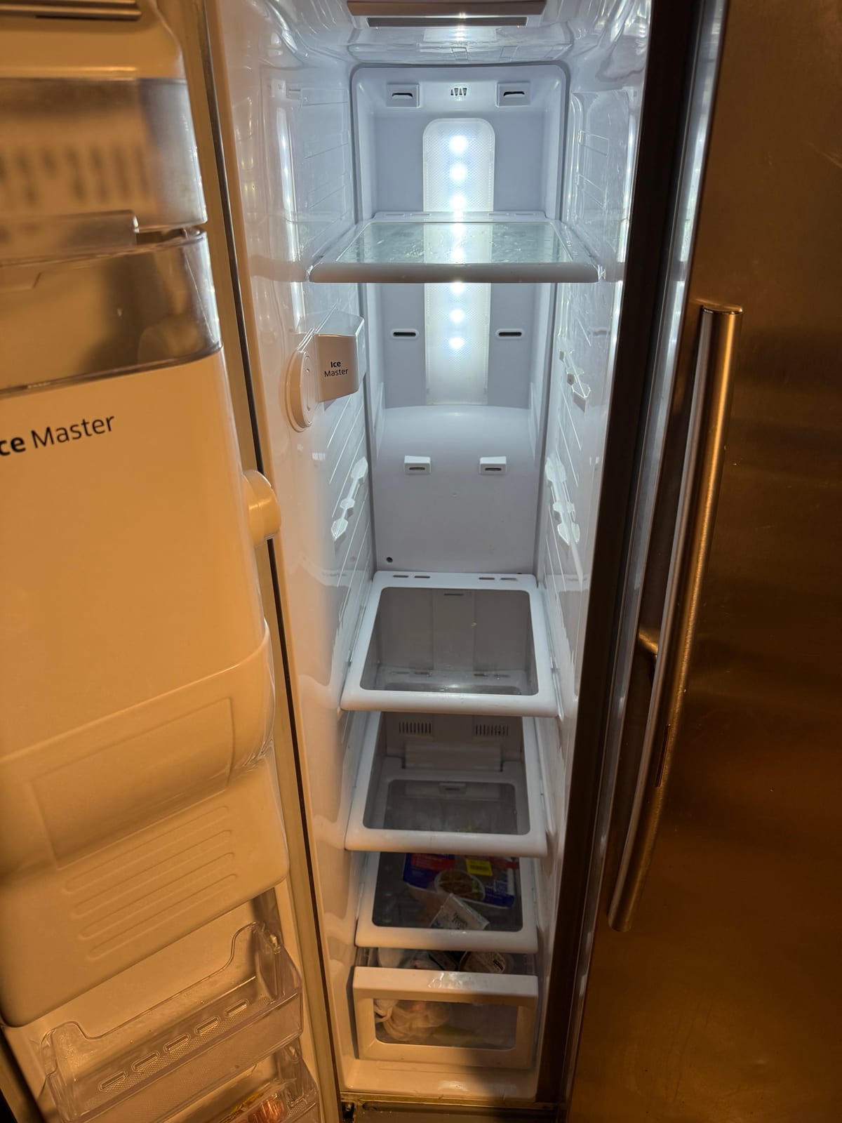 Emptied freezer compartment of a Samsung side-by-side with the Ice Master icemaker at the top