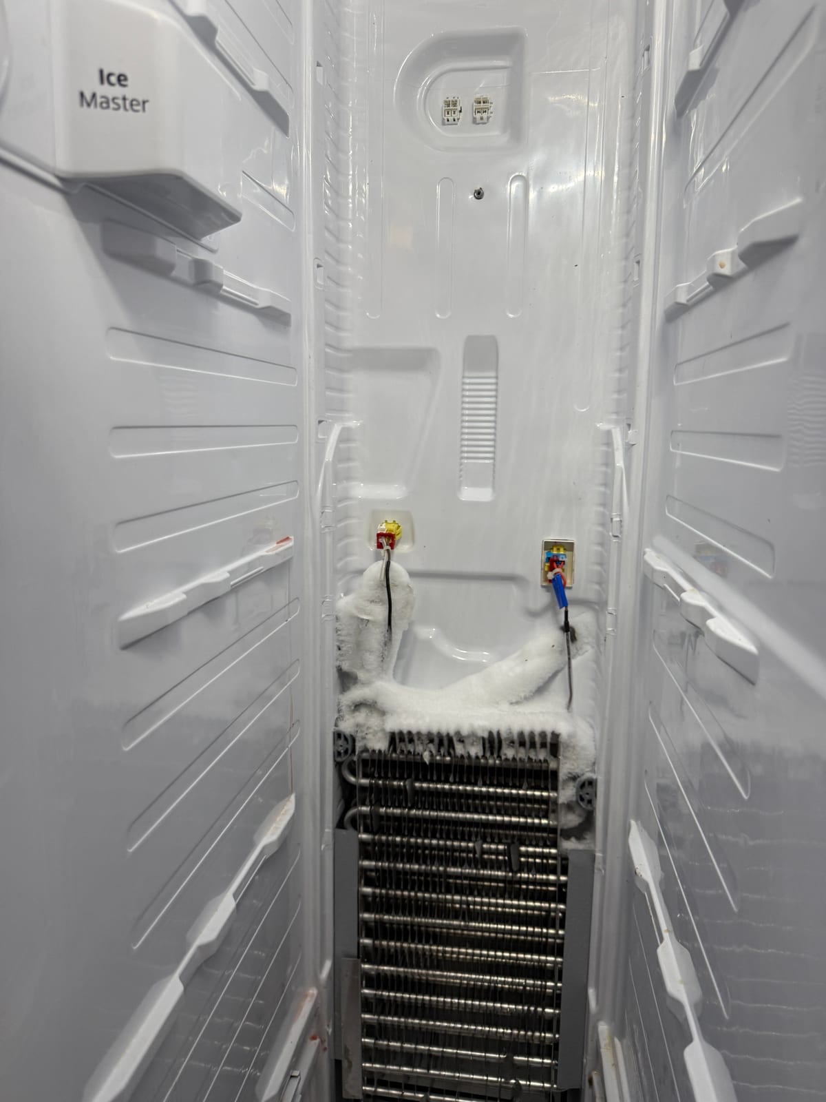 Samsung freezer with the rear cover off, showing frost built up at the top of the evaporator coil