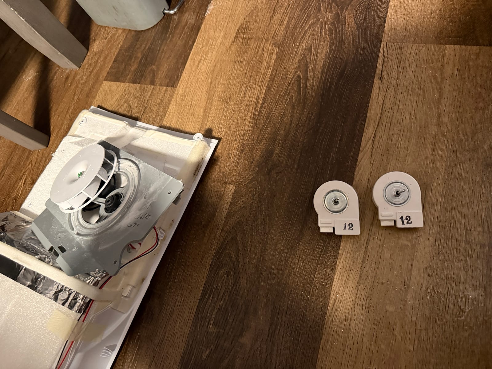 Two Samsung evaporator fan motors side by side on the floor, each marked 12