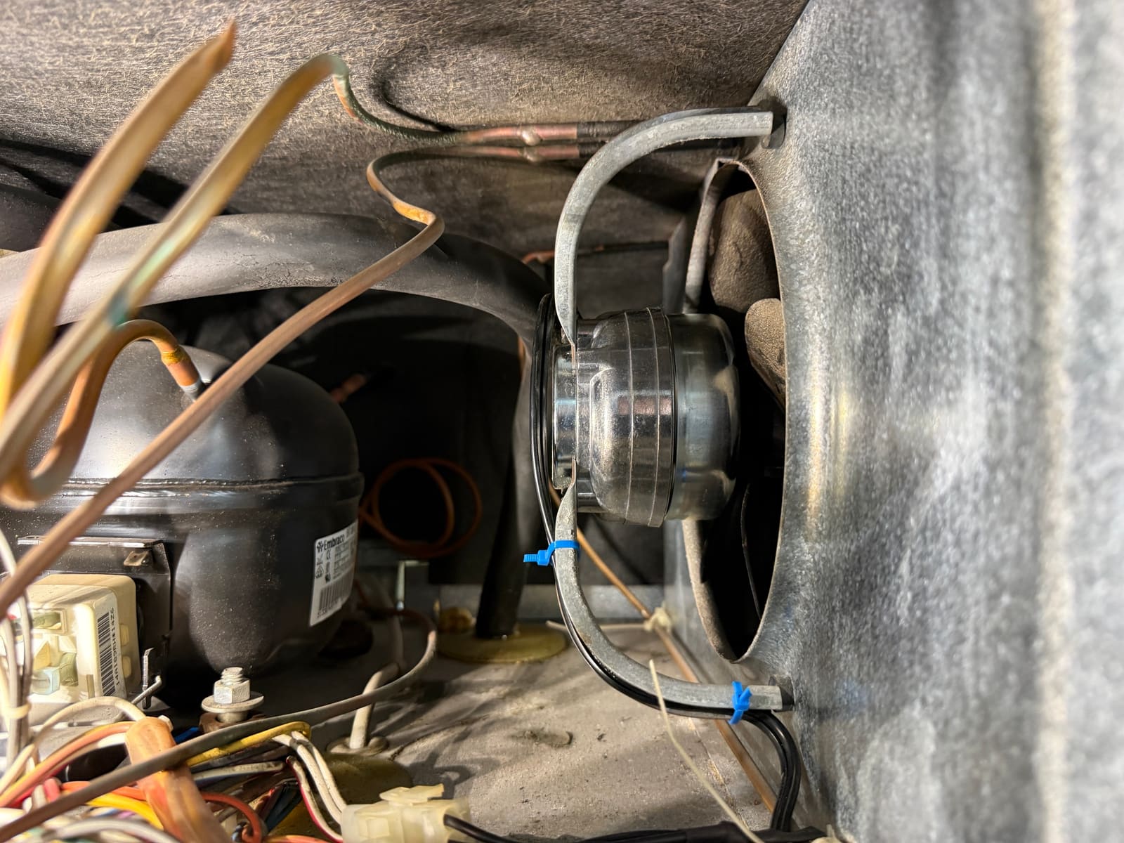 New condenser fan motor installed in its bracket in the Sub-Zero machine compartment, next to the Embraco compressor