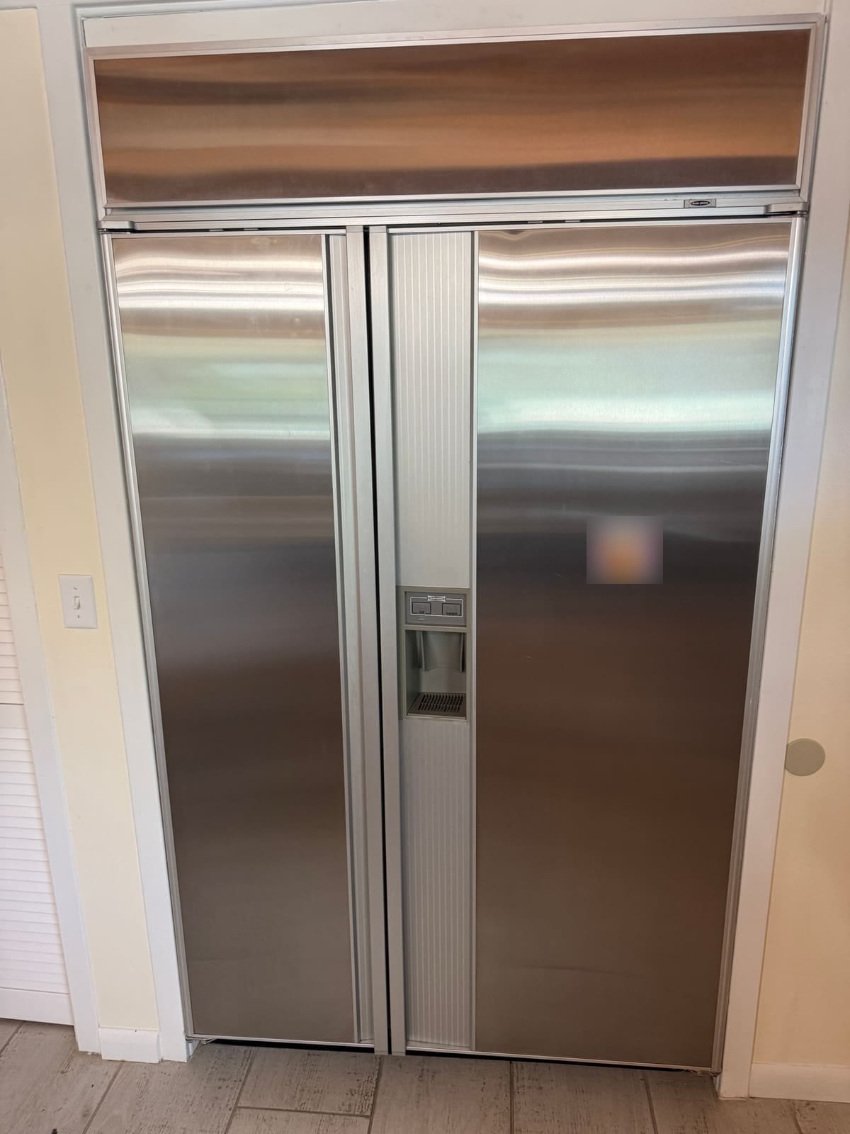 Built-in Sub-Zero 590 side-by-side refrigerator with stainless doors and a water and ice dispenser, in a kitchen in Palm Harbor