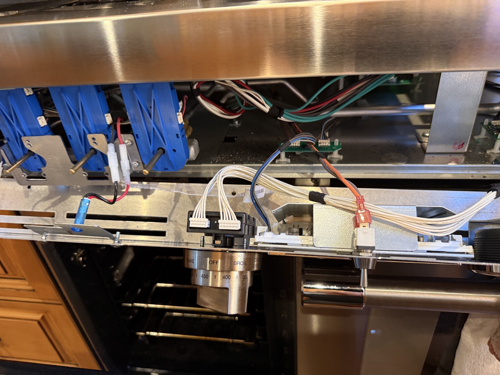 Row of burner valves and wiring behind the Thermador range's control panel