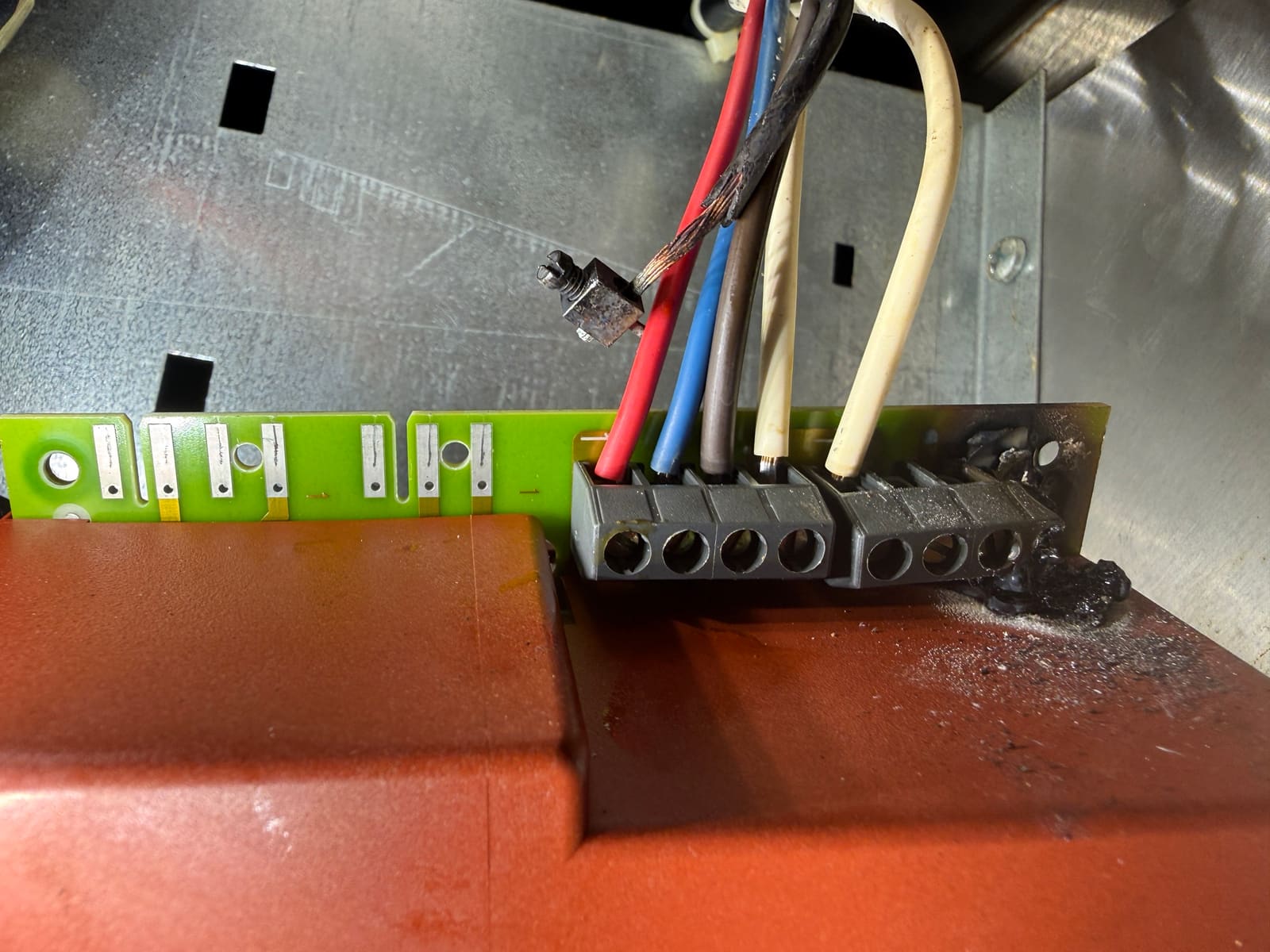 Thermador hood control board with the burned terminal at the end of the terminal block and scorch marks on the control box below