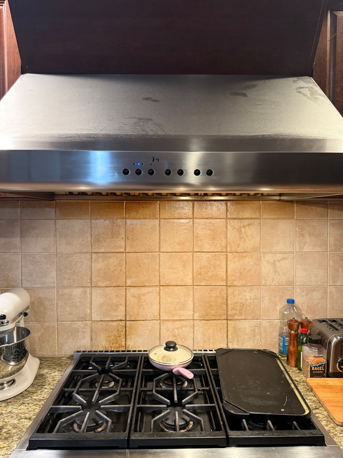 Stainless steel Thermador wall-mount range hood over a gas rangetop in a kitchen in Pinellas County