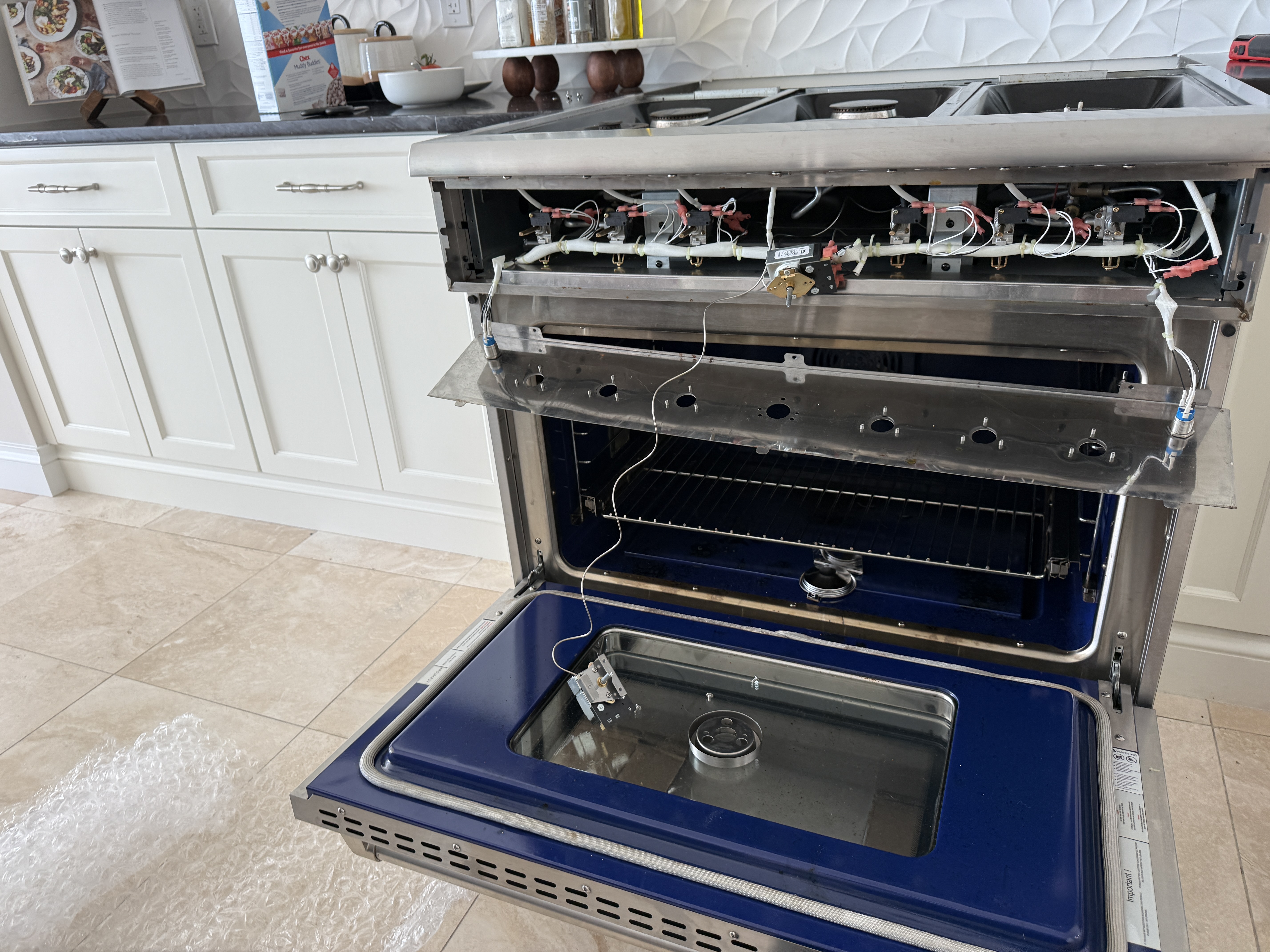 THOR range opened up, showing igniters and the oven thermostat wiring