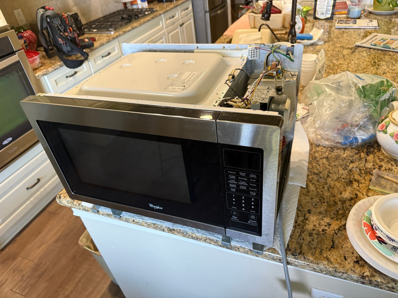 Whirlpool built-in microwave sitting on the kitchen counter with its top cover removed